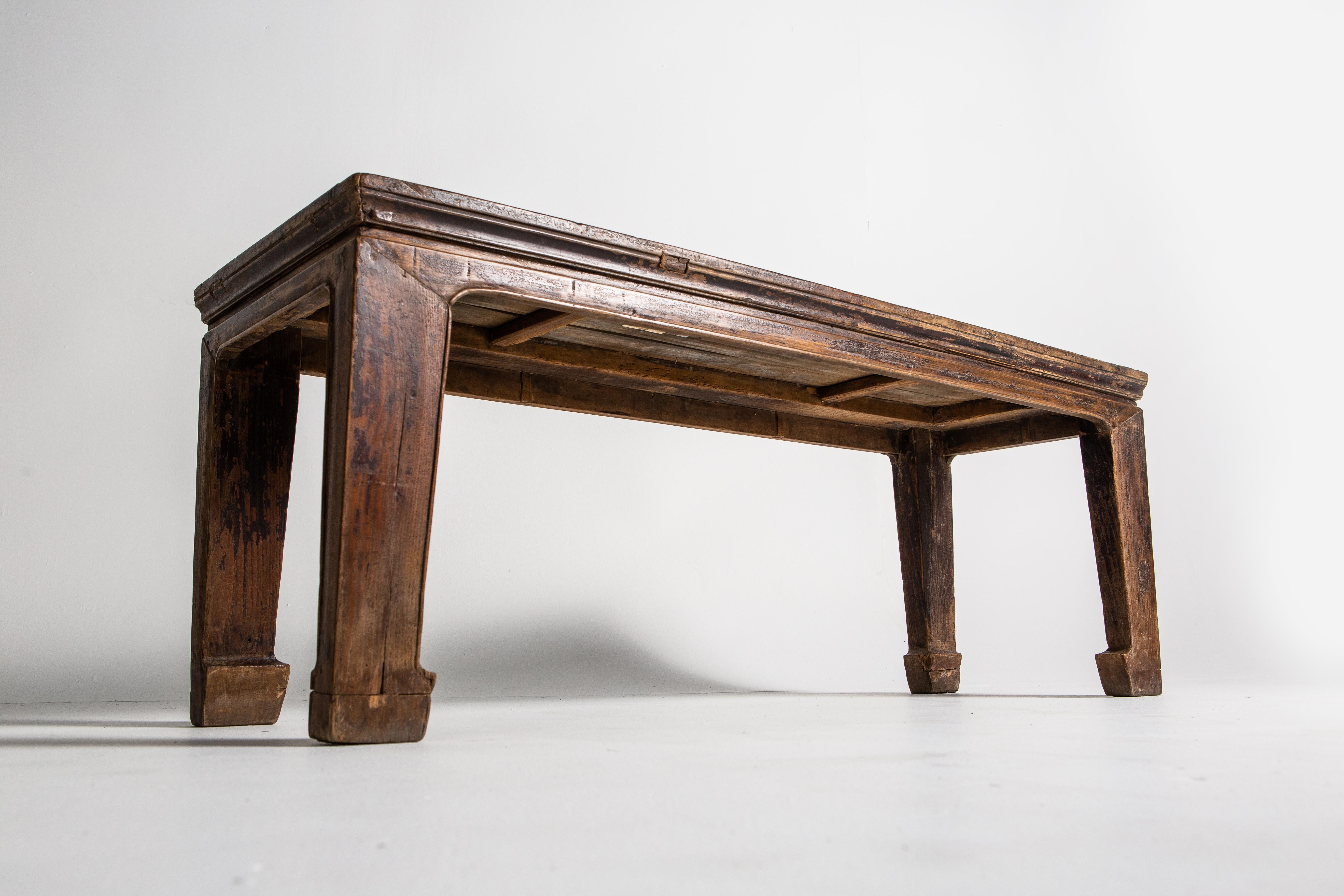 This narrow-waisted elm wood bench features horse hoof legs and an all-original oxblood lacquer finish. Due to long use, much of the original lacquer has worn off, particularly around the feet. The piece can be bees-waxed for a more lustrous finish.