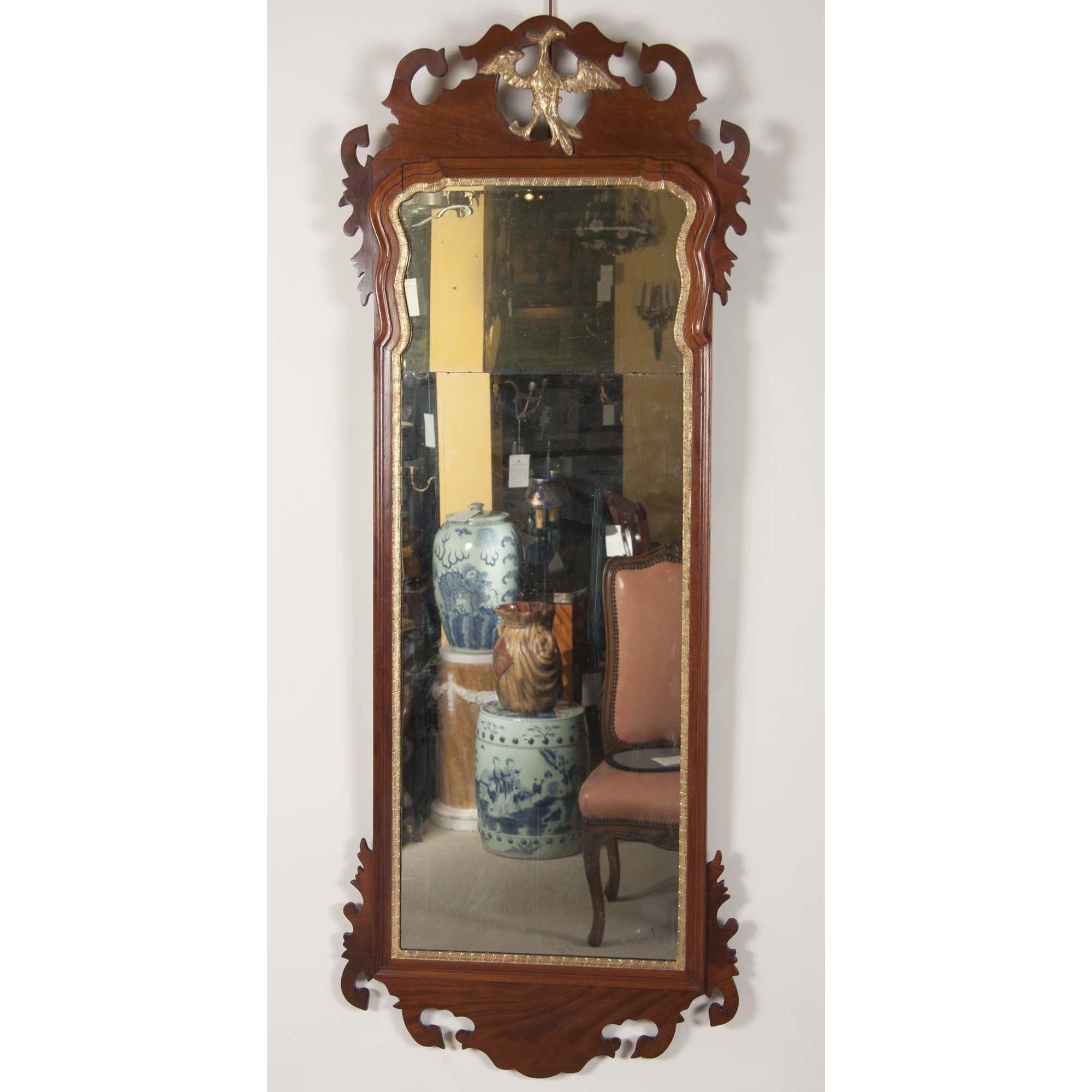 A mahogany Queen Anne pier mirror with carved gilt Phoenix crest, carved shaped and molded frames, and an incused gesso interior border.