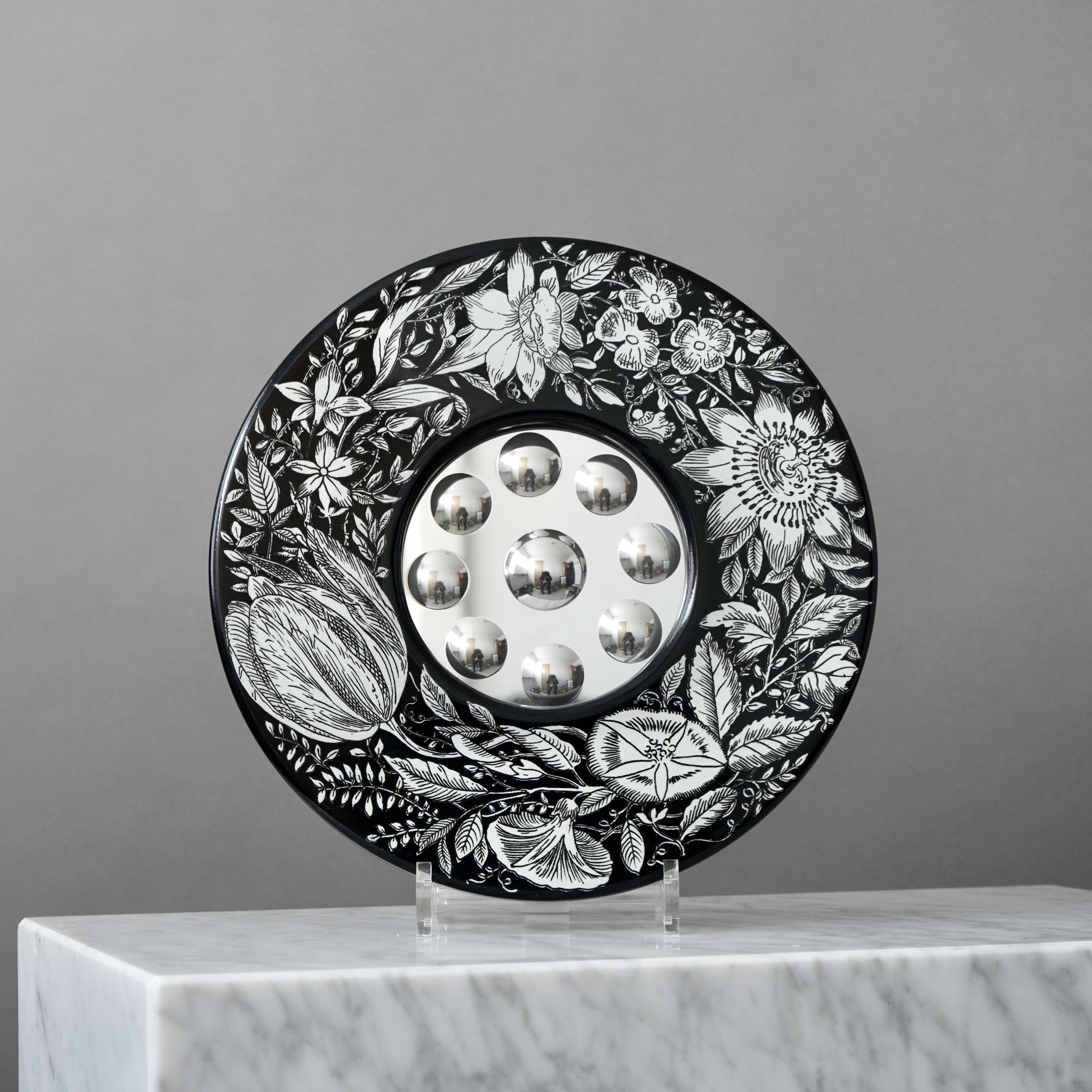 This is an early and rare example of the black and white version of the 'Corona di fiori' wall mirror, with convex optical mirrors.
Designed and produced by Piero Fornasetti in the mid 1950s. In Milano, Italy.

Materials: wooden support covered with