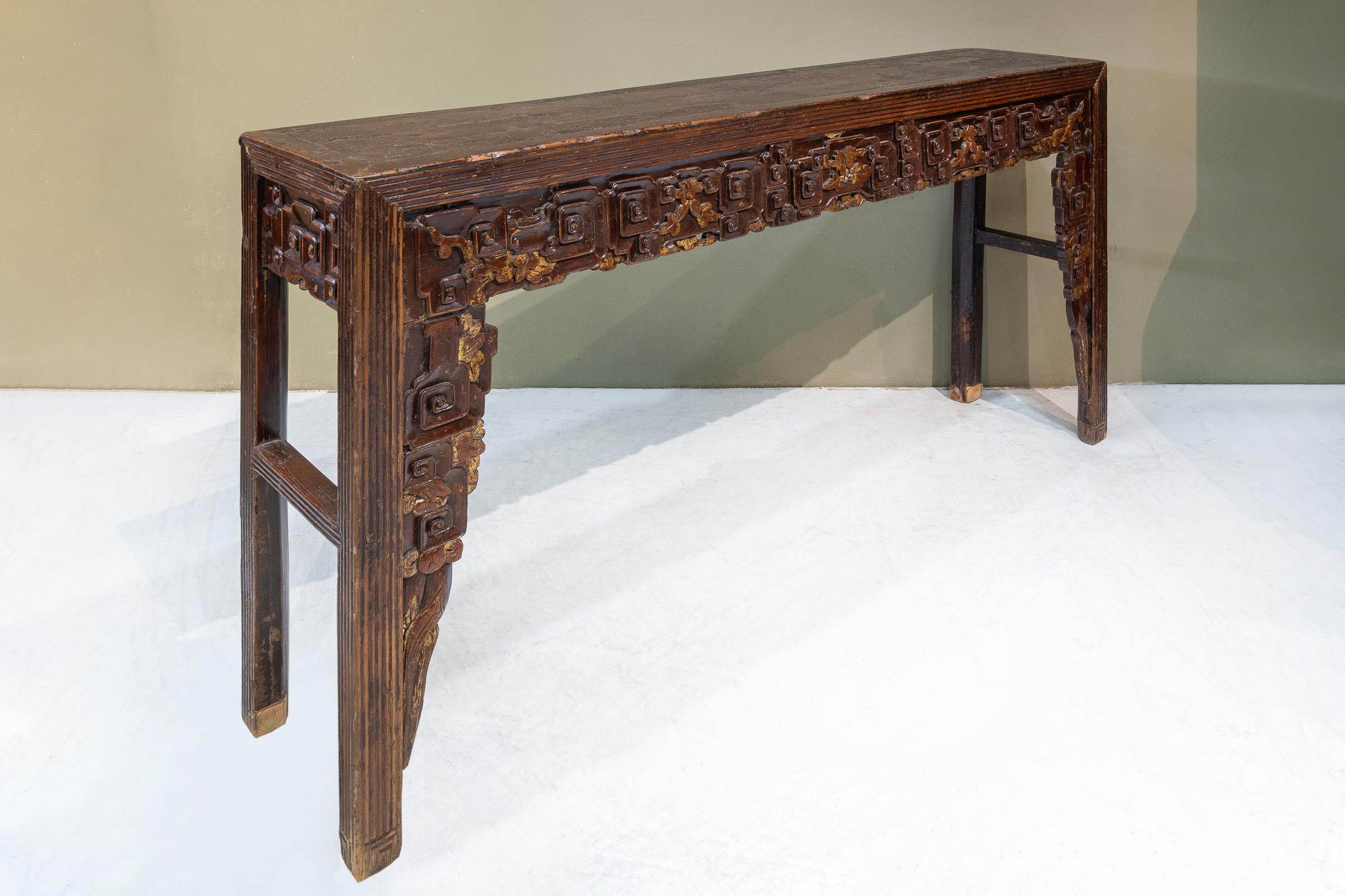 A slim altar table from Chaozhou province, China. This has a very attractive patina, and on the table top you can see the layers of the old lacquer, including a layer of gauze. The relief carvings on the table have a cloud design throughout, it