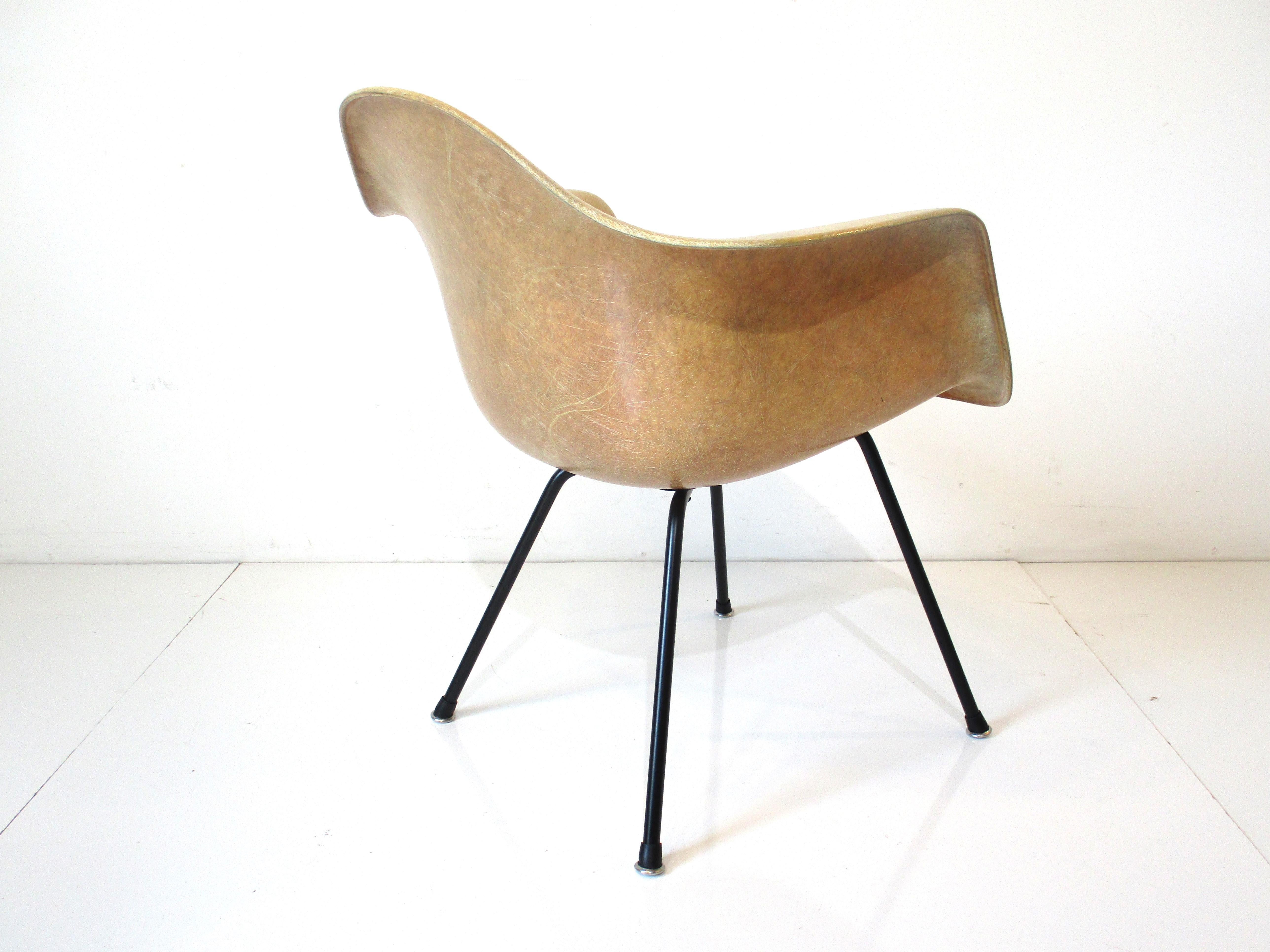 A very early 1st generation rope edge rare lounge height fiberglass arm shell chair with the larger rubber shock mounts having metal washers and satin black iron X base. The chair still retains the four squares manufactures label made by the Herman