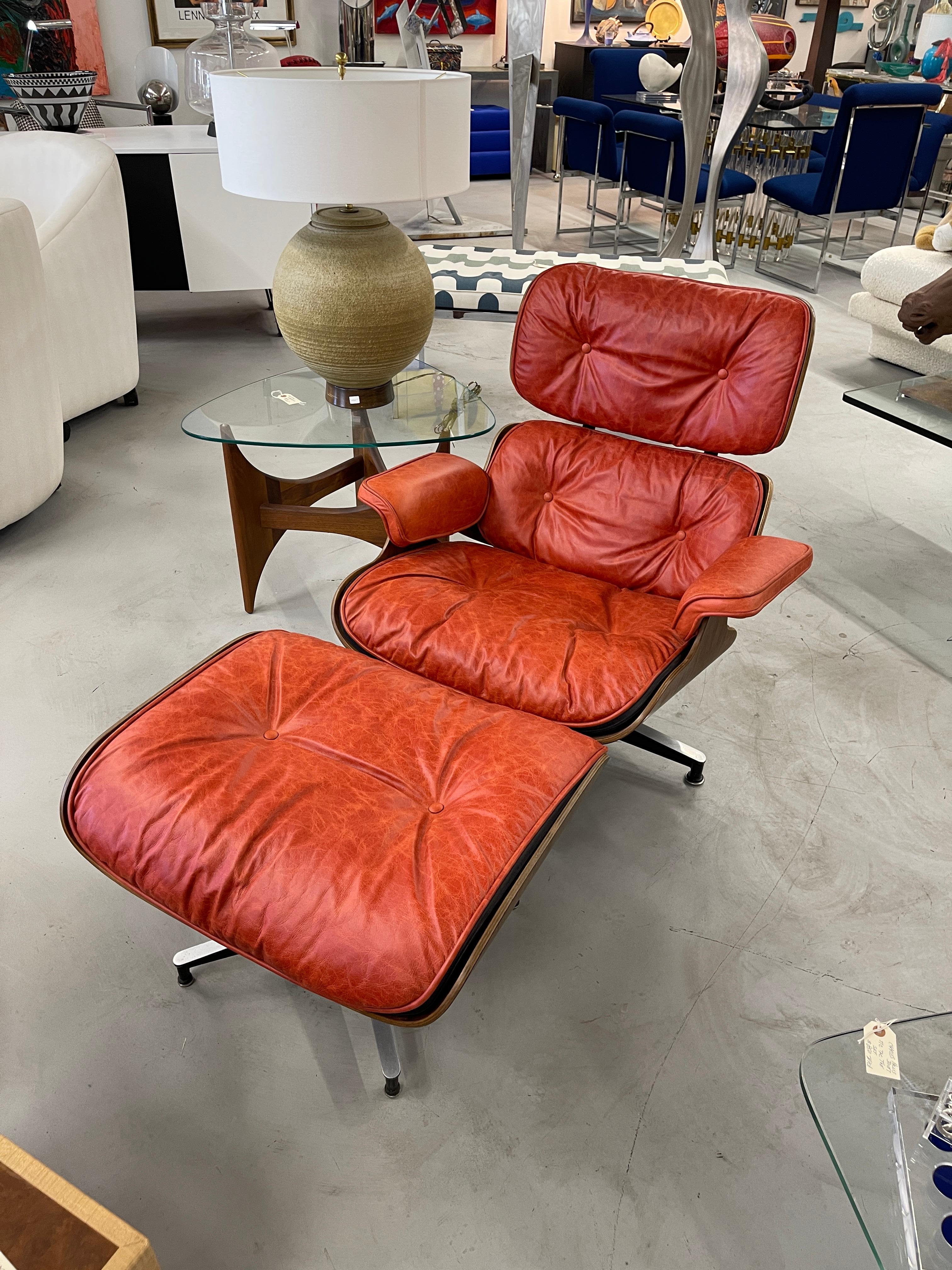 Beautiful rosewood Charles and Ray Eames 670/671 Lounge Chair and Ottoman it has been redone in a lovely coral red color. The rosewood shells are stunningly grained. They have very little fading. There are some minor chips to the edges. The metal