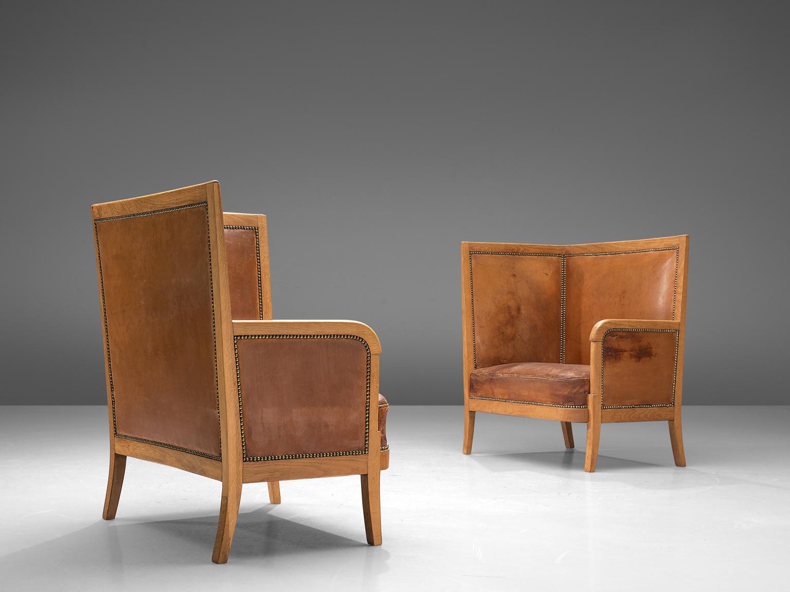 Set of two lounge chairs, in oak and cognac leather, Scandinavia, 1940s. 

Set of two high back chairs upholstered in high quality cognac leather. This luxurious set is made of an oak frame with nice round shapes and lines. The aesthetics of this