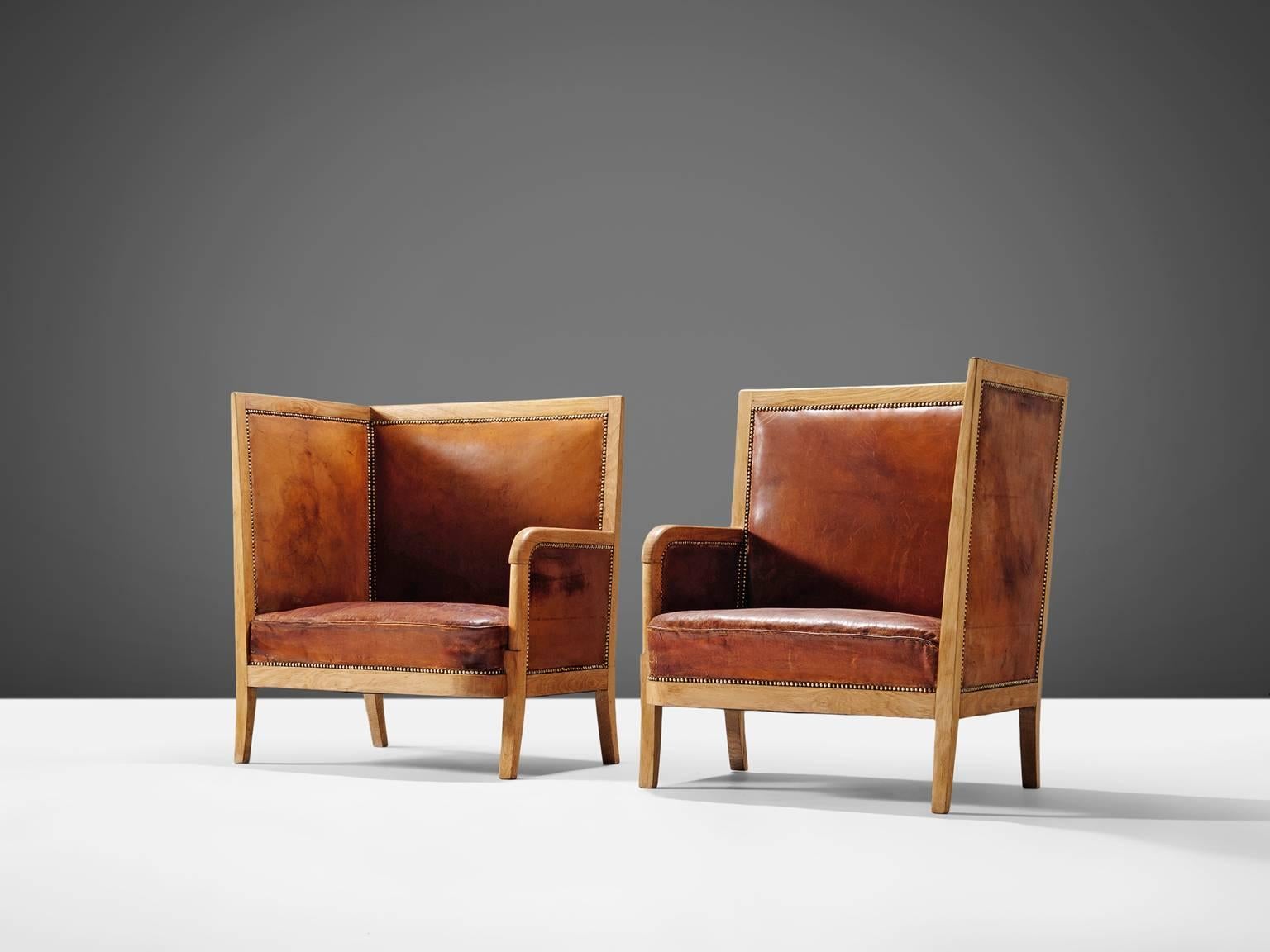 Set of two lounge chairs, in oak and cognac leather, Scandinavia, 1940s. 

Set of two high back chairs upholstered in high quality cognac leather. This luxurious set is made of an oak frame with nice round shapes and lines. The aesthetics of this