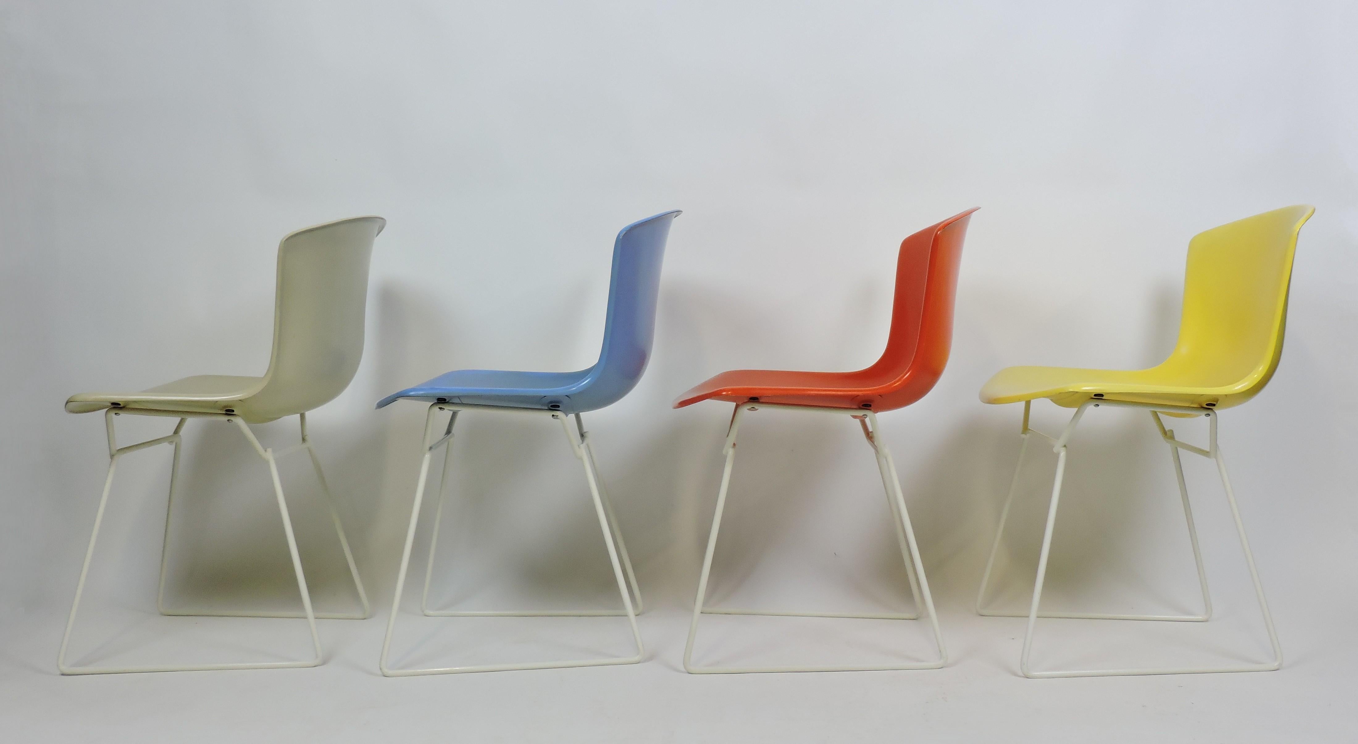 Satz von vier geformten Schalenstühlen, entworfen von Harry Bertoia und hergestellt von Knoll. Dieses sehr frühe Set, das 1960 auf den Markt kam, stammt aus dem Jahr 1963 und enthält vier Farben - Beige, Blau, Rot und Gelb - auf einem weißen Rahmen,