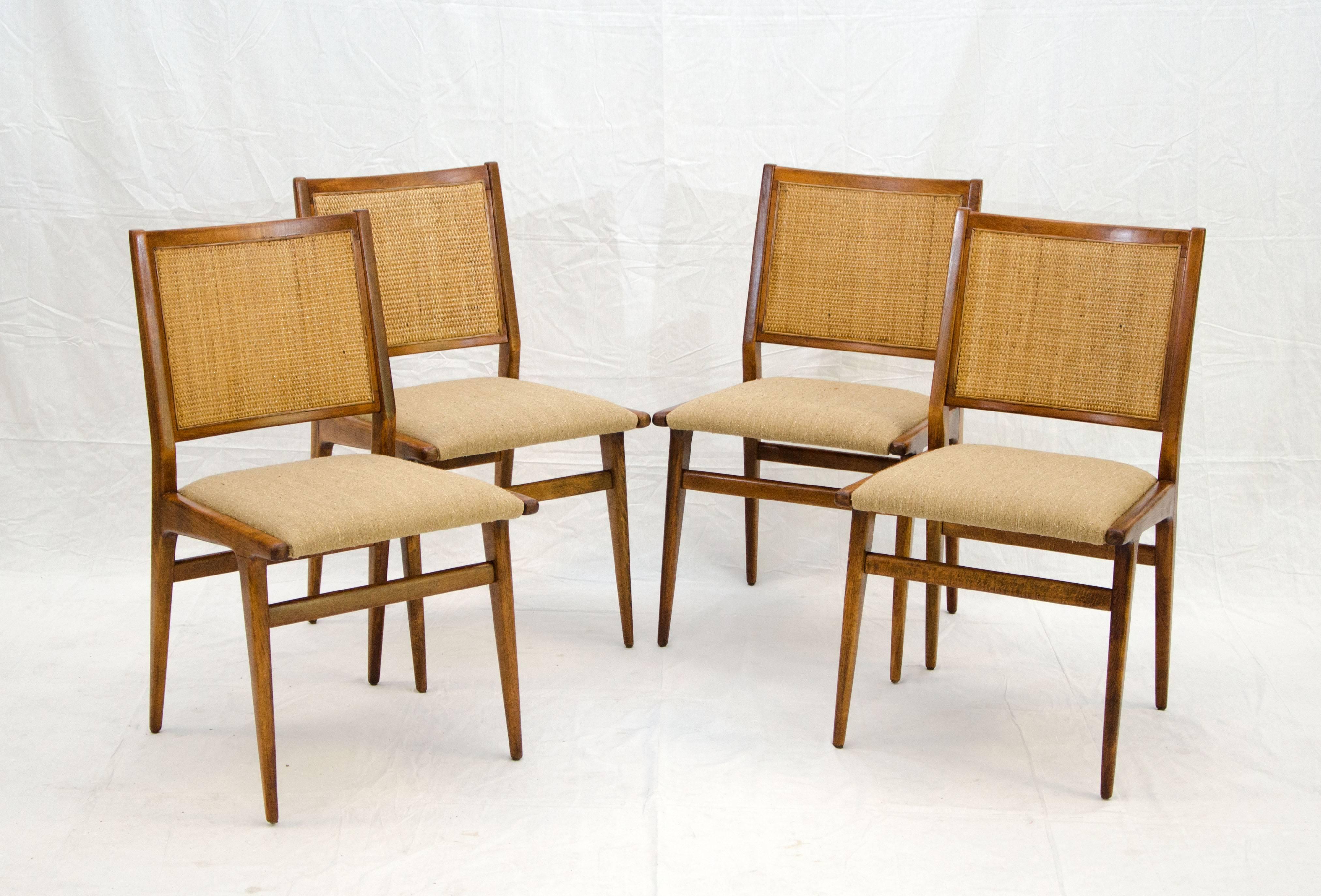 Beautiful set of four Jens Risom dining chairs. The caned backs are original. The seat design is very angular and the birch chair frames were restored with a very light walnut finish. The new light sand colored upholstery offsets both the cane and