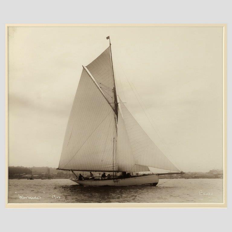 Early silver gelatin photograph print of the Gaff rigged yacht wayward sailing on port tack with Cowes in the background by Beken of Cowes.

Signed and dated 1902.