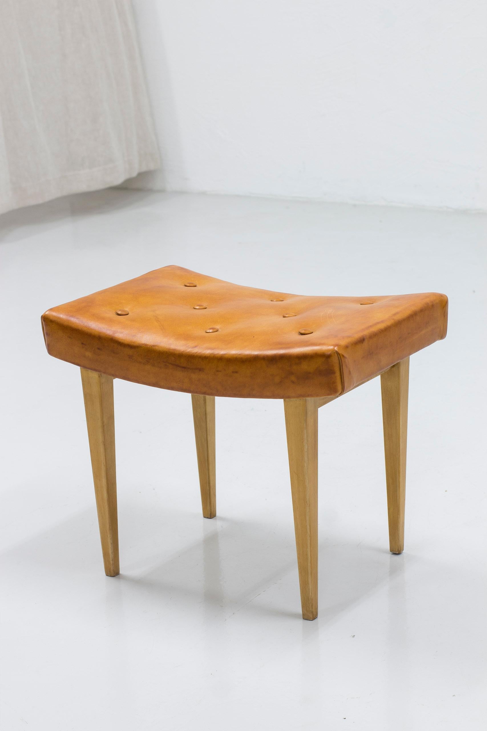 Early stool designed by Bruno Mathsson. Produced by Firma Karl Mathsson in 1941. Very early example with paper label, hand signed BM -41 for the manufacturing  year, 1941. Made from birch and upholstered in cognac leather. Very good vintage