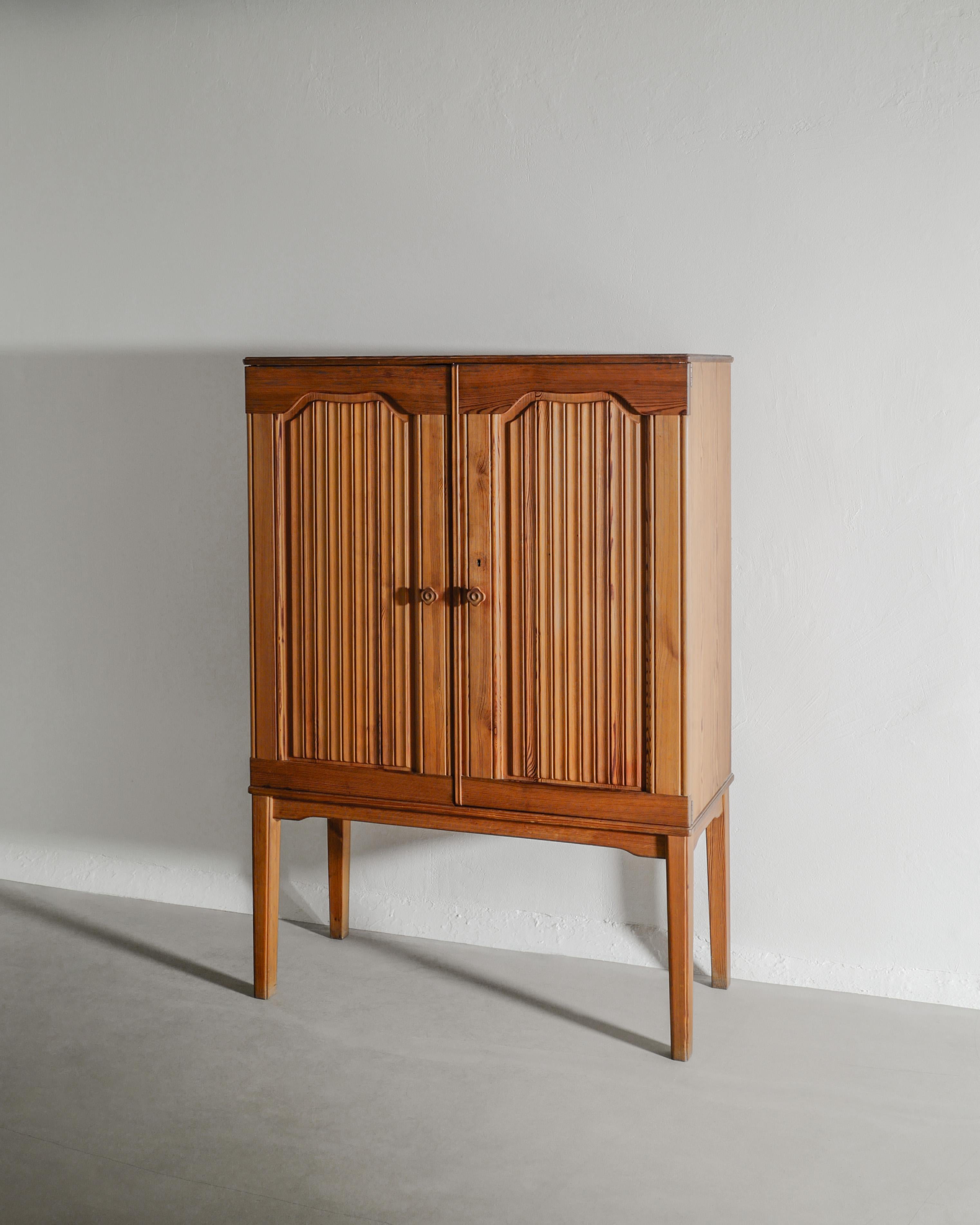 Ein sehr seltener moderner schwedischer Kiefernholzschrank mit traditionellen und dekorativen Doppeltüren, Einlegeböden, Schubladen und zwei blumenförmigen Griffen, entworfen und gebrandmarkt von Carl Malmsten, hergestellt in Schweden, 1930er Jahre