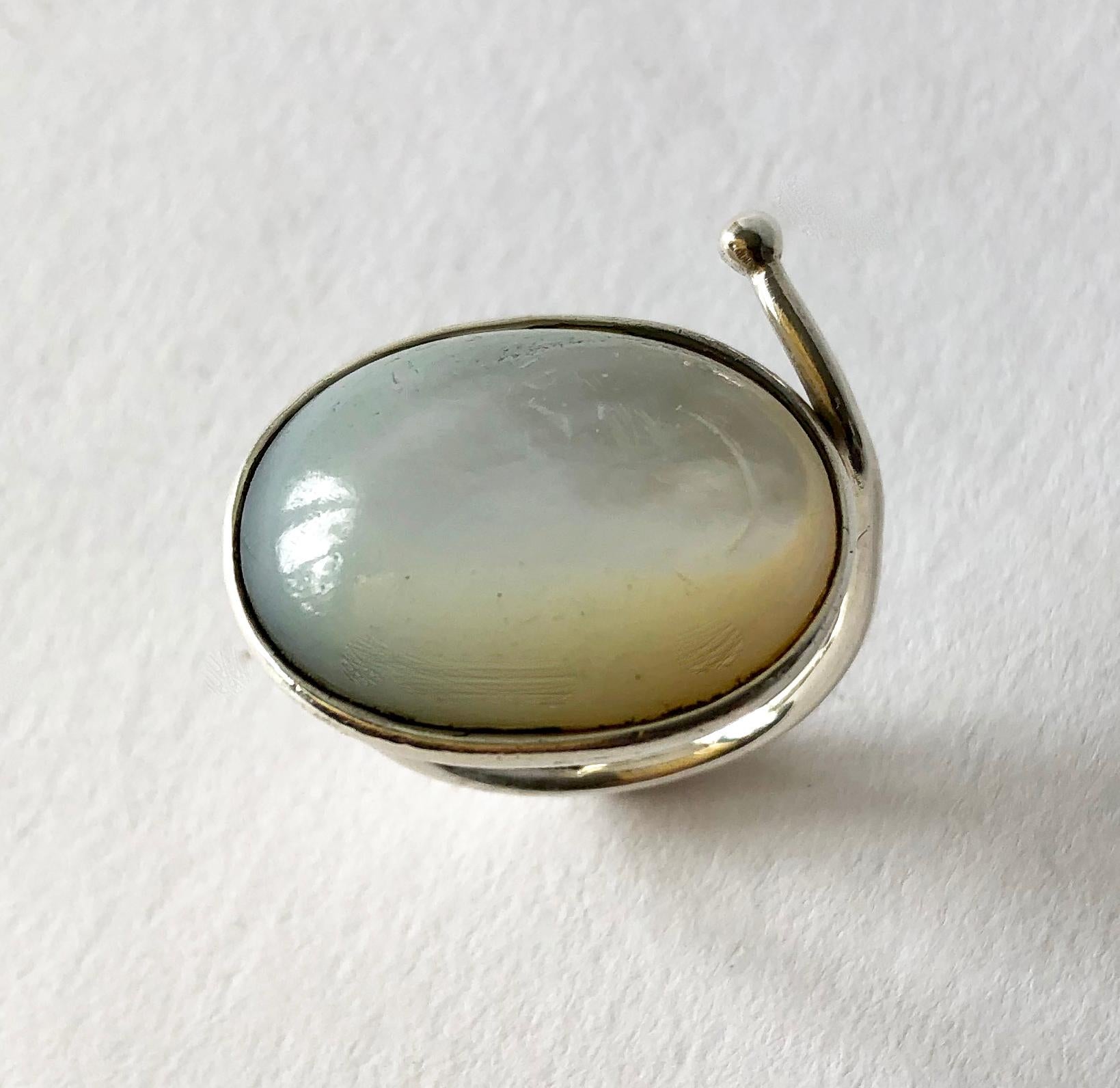 Luminescent mother of pearl stone set in sterling silver created by Vivianna Torun Bülow-Hübe. Ring is a finger size 9 - 9.25 due to its unusual shape.  Signed Torun, Sterling. In very good vintage condition showing some wear to the silver conducive