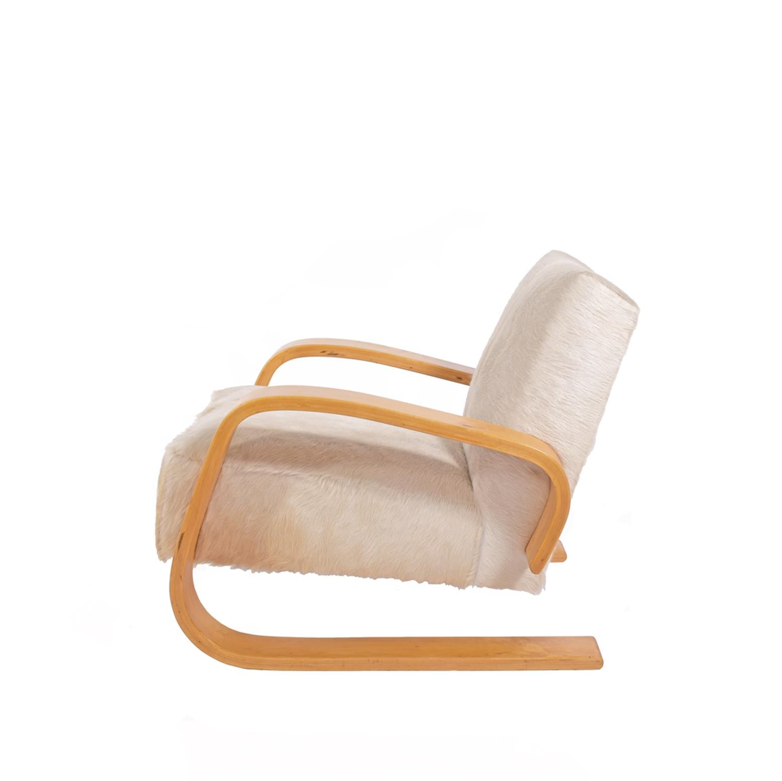 Early Tank chair with birch arms and spring construction seat and back. Reupholstered in cowhide. Made by Artek. This chair was produced between 1940 and 1955.
