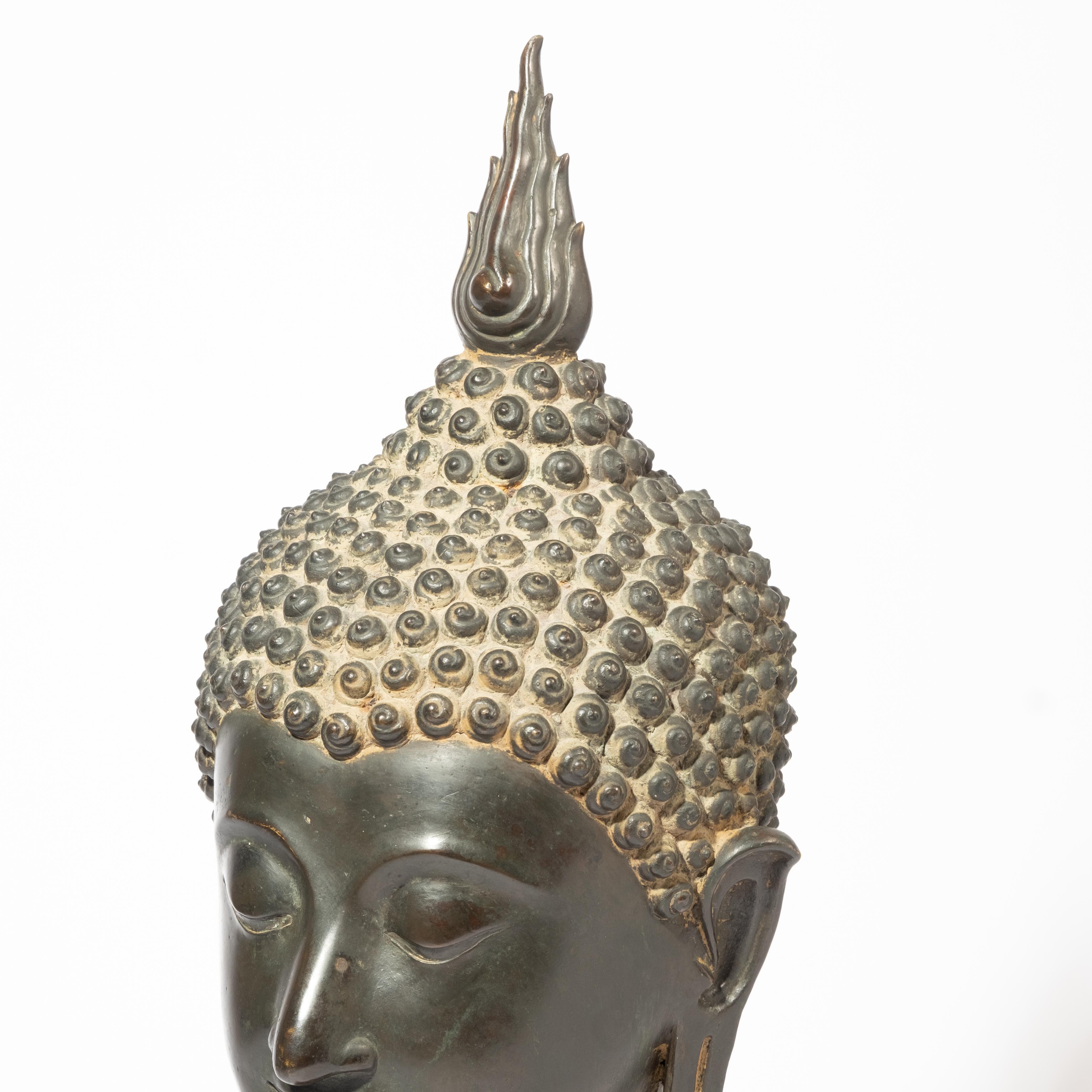 Large Ancient Sukhothai Bronze Buddha Head. Excellent Example likely 15th c., Probably Thailand, in classic Sukhothai style, with serene expression, downcast eyes and flame of enlightenment on top of ushnisha, egg-shaped head, tight curls arched