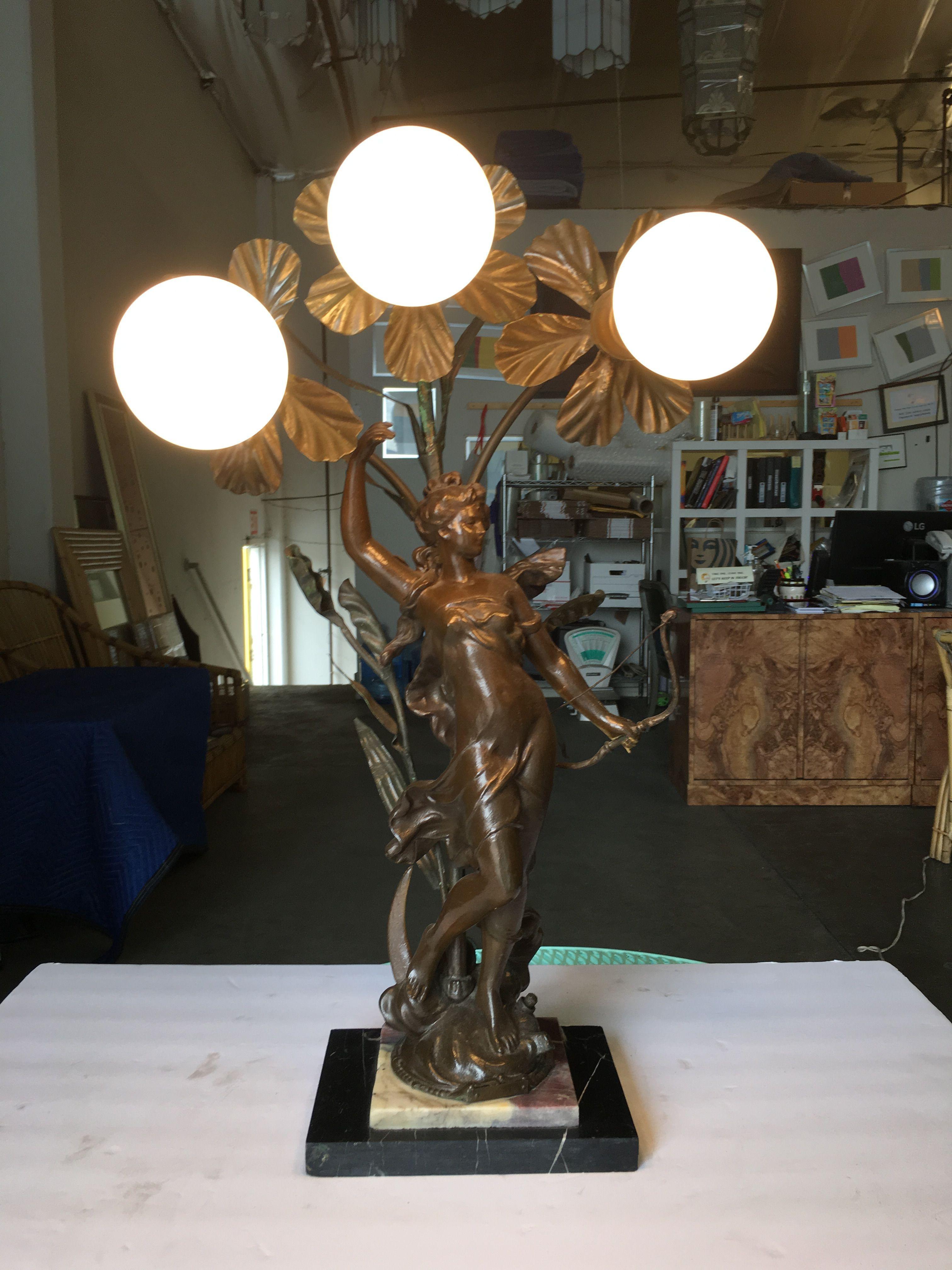 Early three bulb Art Nouveau figural table lamp featuring a beautiful figural casted bronze female fixed to a two-piece, two-tone marble base topped with an organic freeform floral featuring 3 standard light sockets.