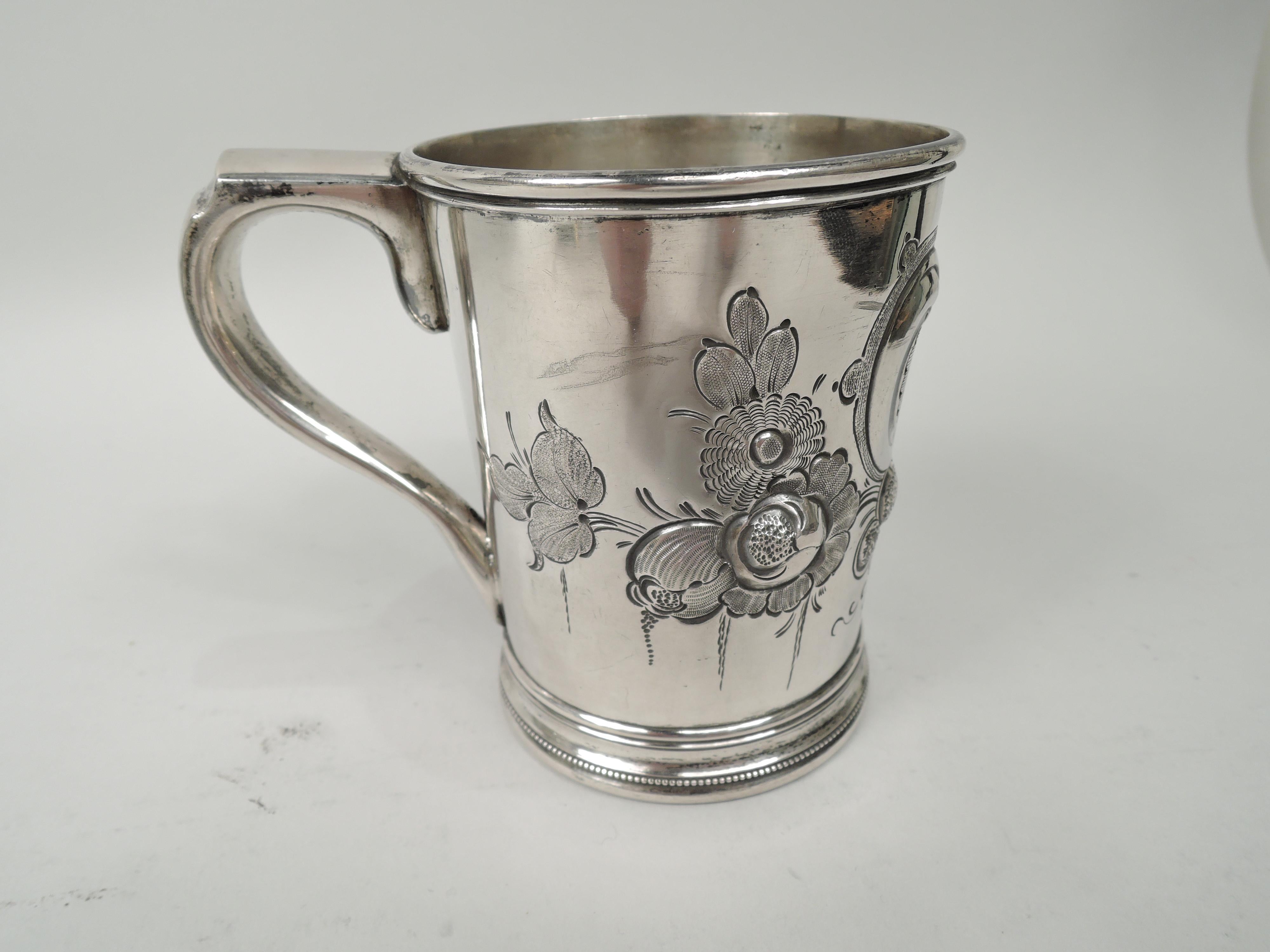 Large Classical coin silver baby cup. Made by Grosjean & Woodward for Tiffany & Co. in New York, ca 1855. Gently tapering sides with molded and beaded foot and scroll bracket handle. Chased leafing scroll frame (vacant) with flowers. Maker’s and