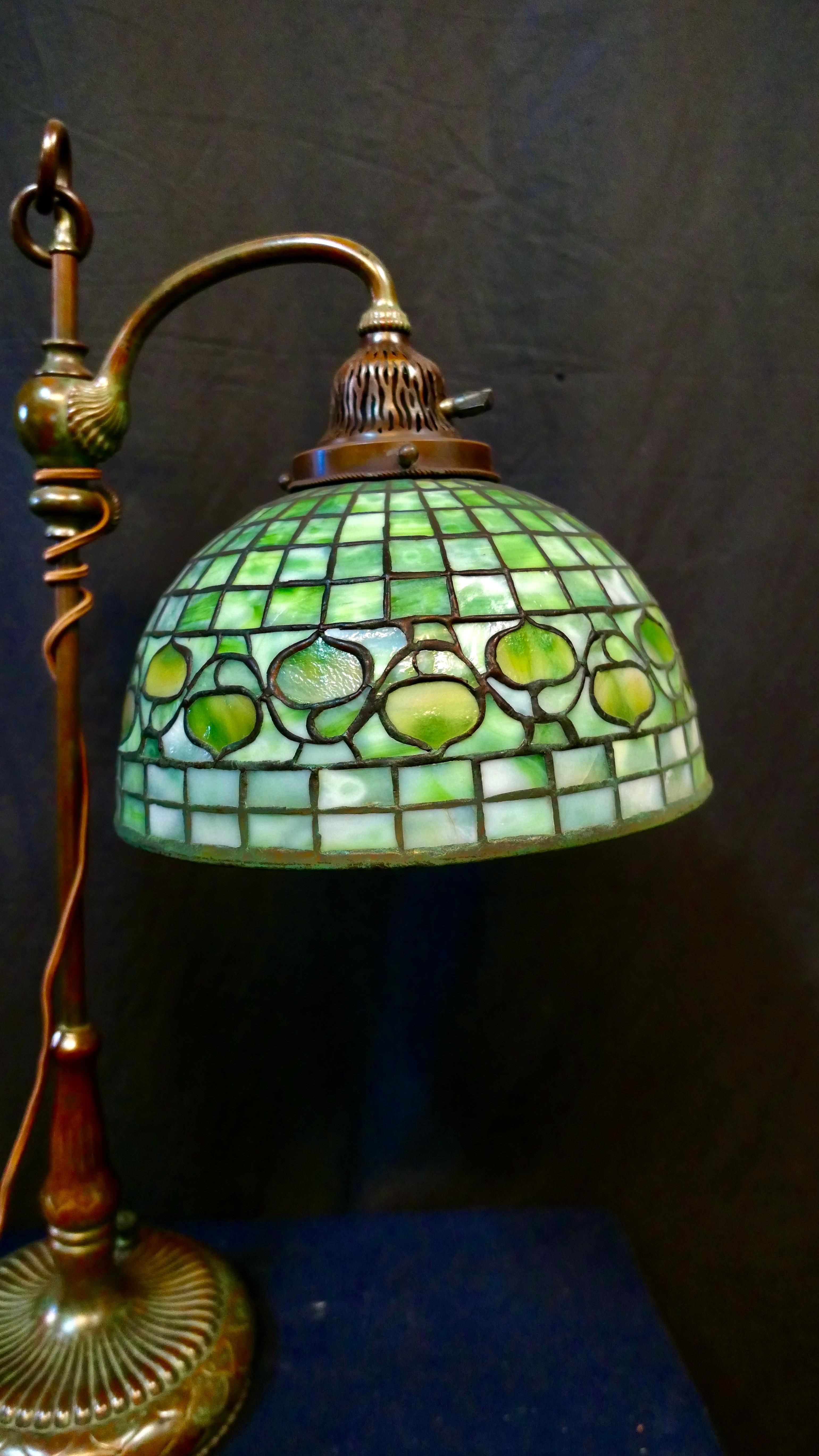 This stylish vintage Tiffany Studios, New York original table lamp is beautifully designed with a colorful Acorn banded favrile art glass shade. This leaded shade decorates a patinated tall & slender adjustable bronze lamp base. The shade is stamped