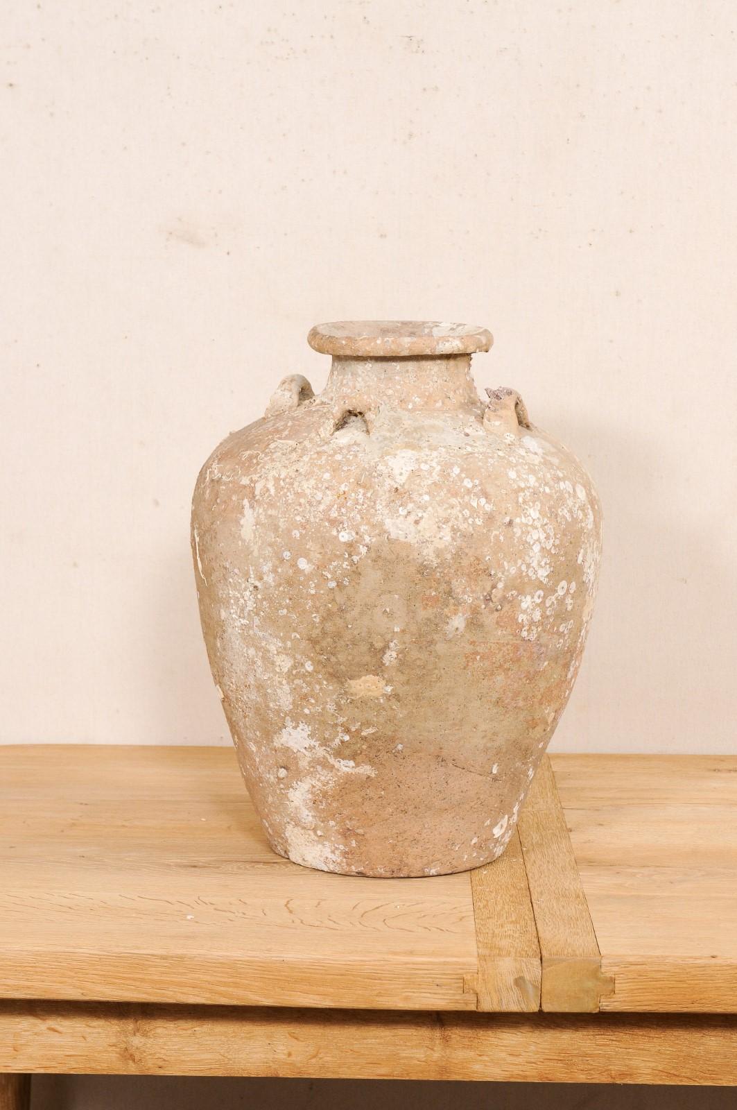 This early to mid 16th century ceramic vessel from Thailand is an excellent specimen of a salvaged ceramic jar from a shipwreck during in the Ming gap period. This antique jar from Thailand stands just over 2 feet in height and has a rounded body,