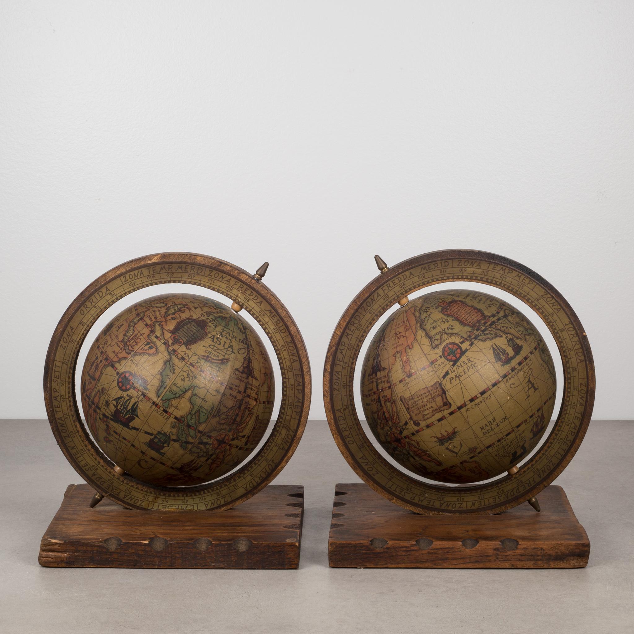 Pair of globe bookends mounted on a rustic, notched wooden base. The globes appear to be metal wrapped in paper. Both globes rotate on their axis. The axis tips are brass on both ends. Original green felt on the bottom.