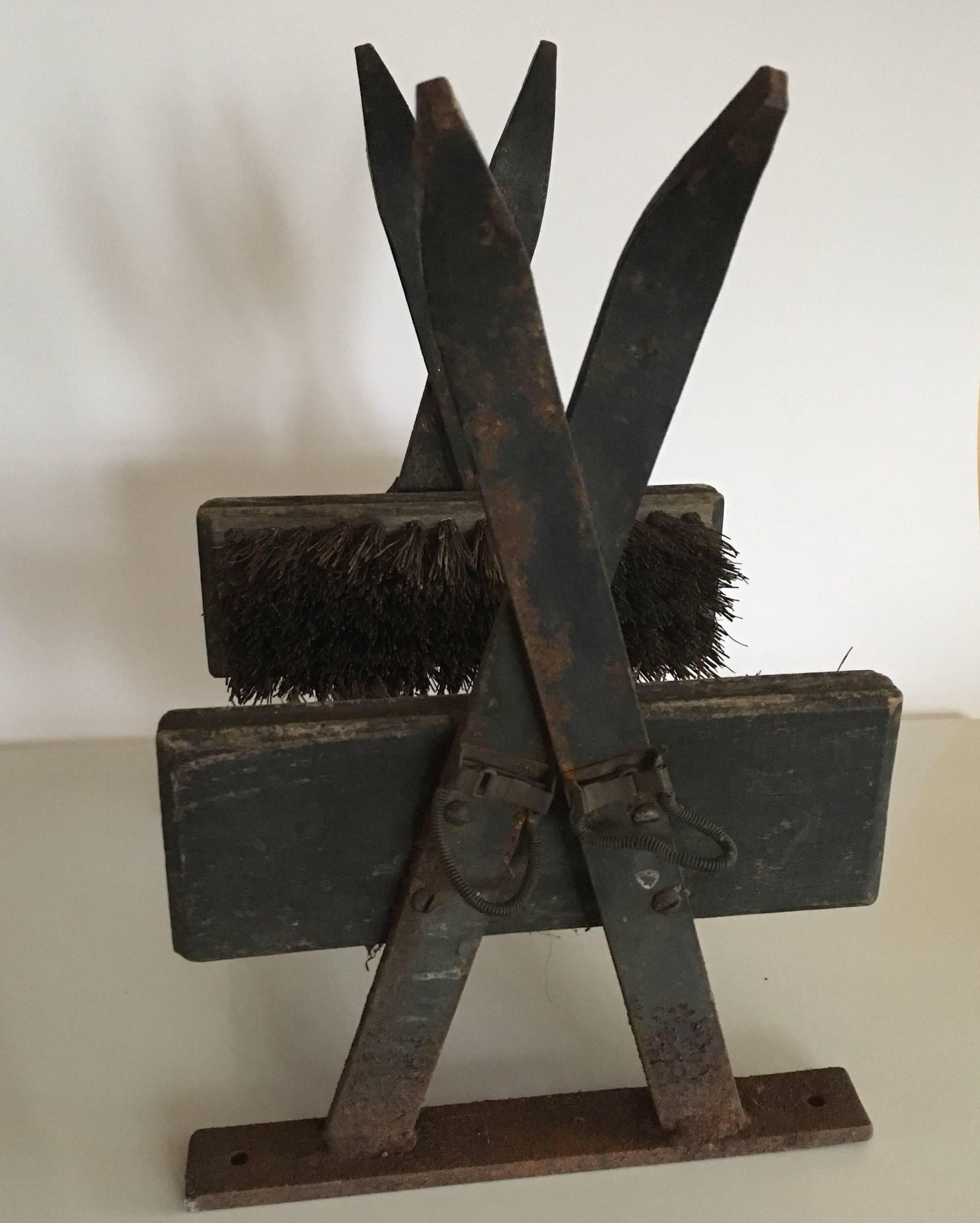Vintage ski lodge iron boot scrape, early to midcentury, a bracket of cast iron (or steel) crossed skis holding a pair of brushes with stiff bristle and wooden backs. Great style overall including the old style cable boot bindings. In very good used