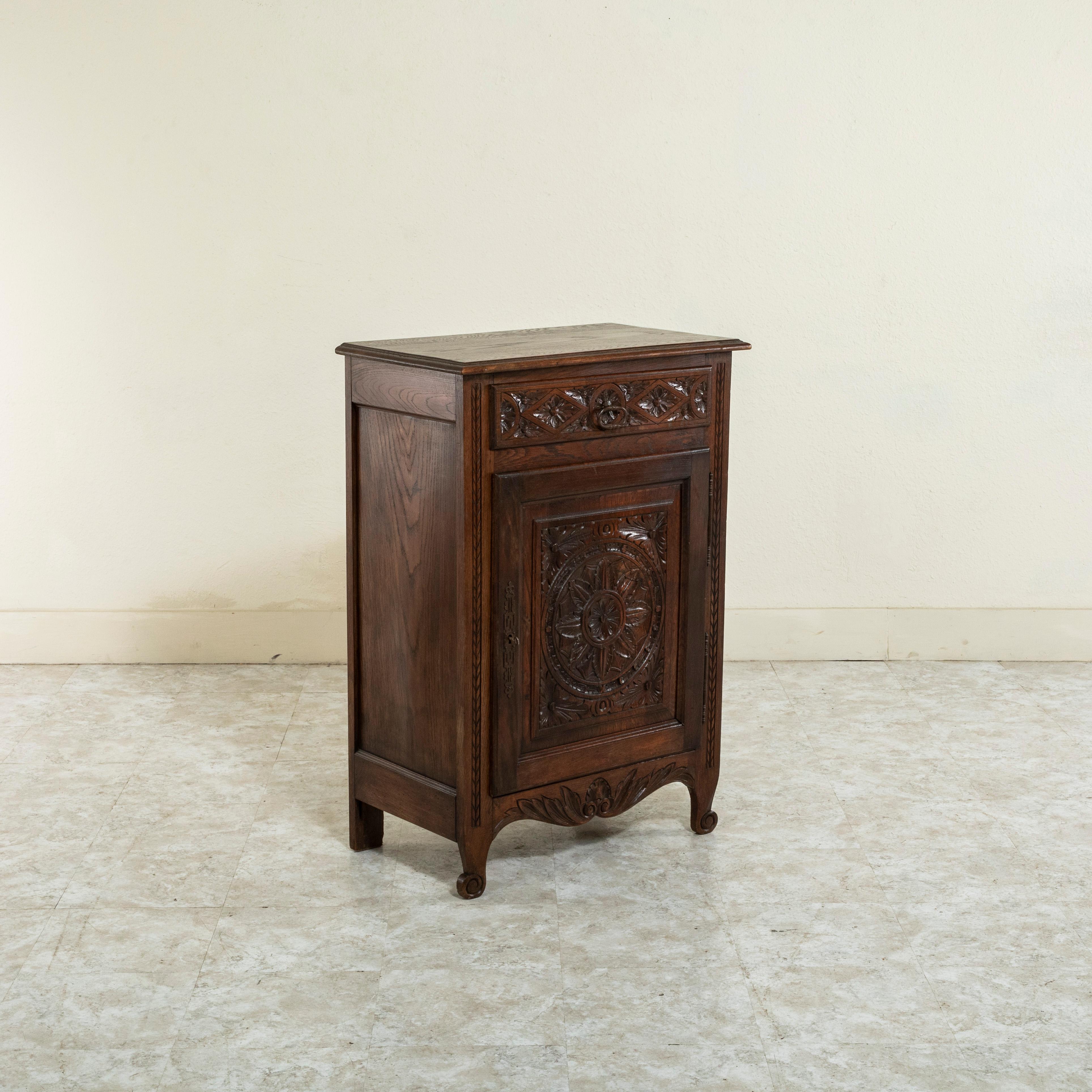 From the region of Brittany, France, this early twentieth century oak jam cabinet features hand carved regional details of rosettes and acanthus leaves on its facade. A single drawer below the beveled top opens with an iron drop ring drawer pull.