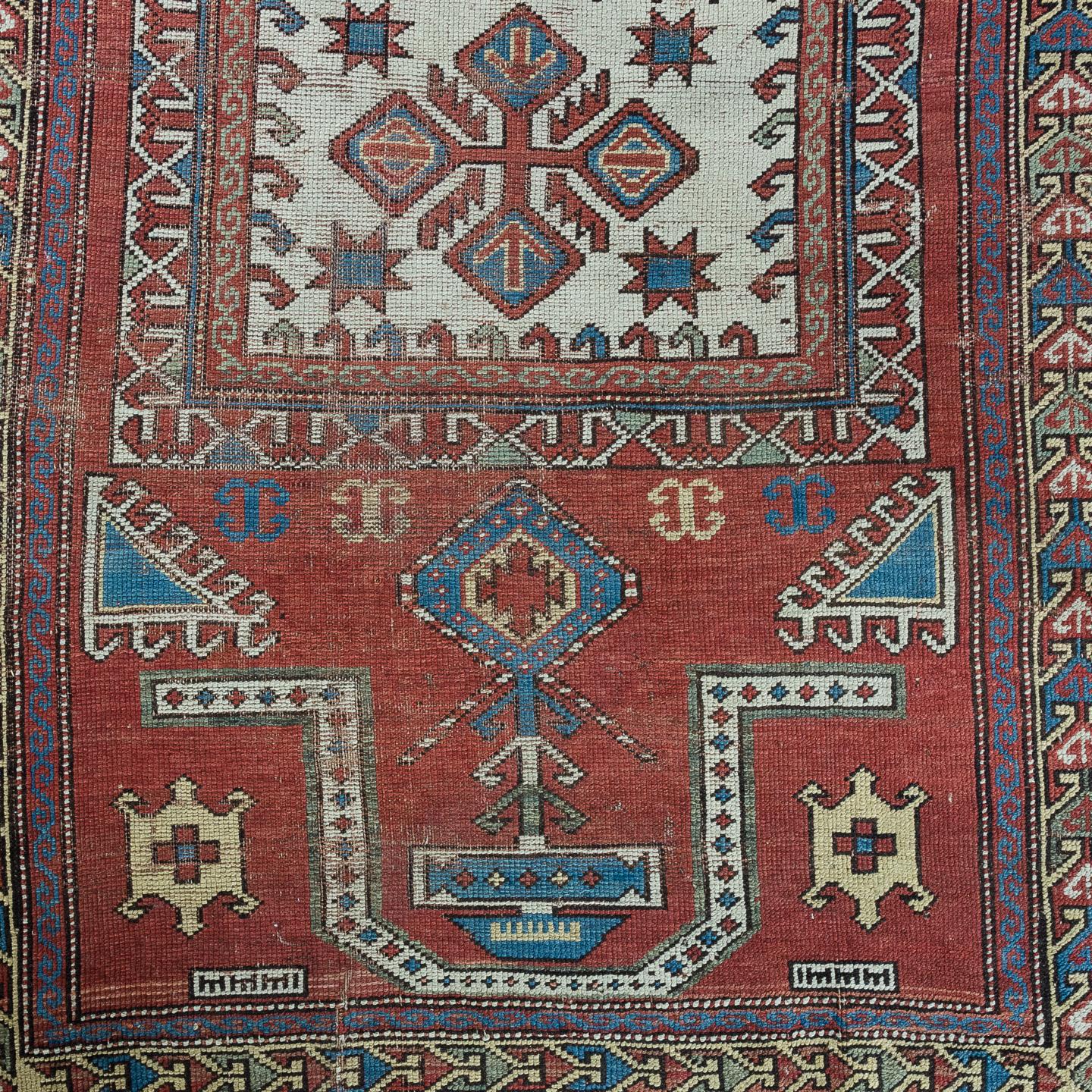 An early 20th century Kazak prayer rug, Caucasian, the deep red ground with geometric decoration and repeating border.