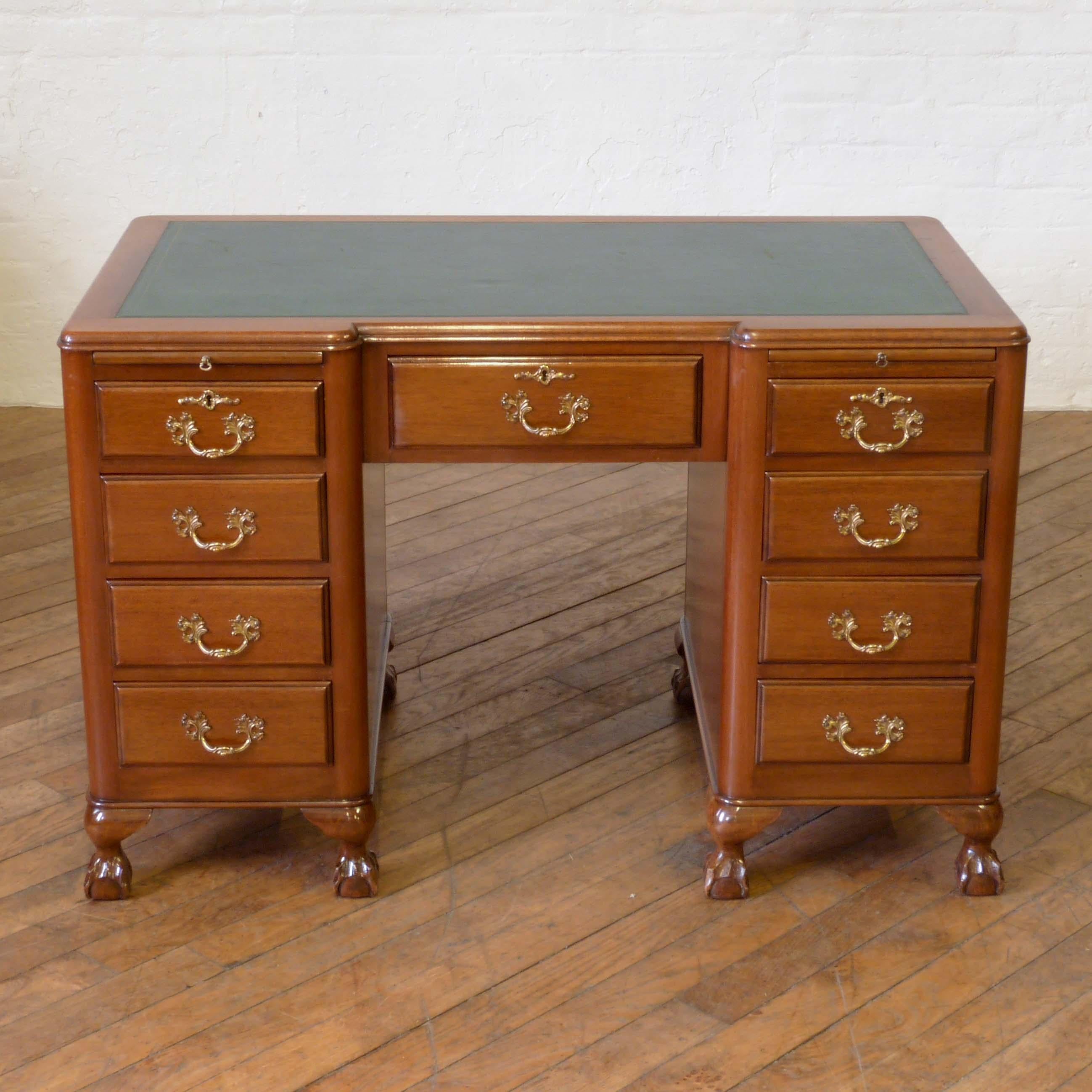 An attractive mahogany desk with seven drawers and two slides. Of inverted breakfront design and sat on ball and claw feet, the handles give it an elegant French look although this desk is of English craftsmanship. The polished back will allow use