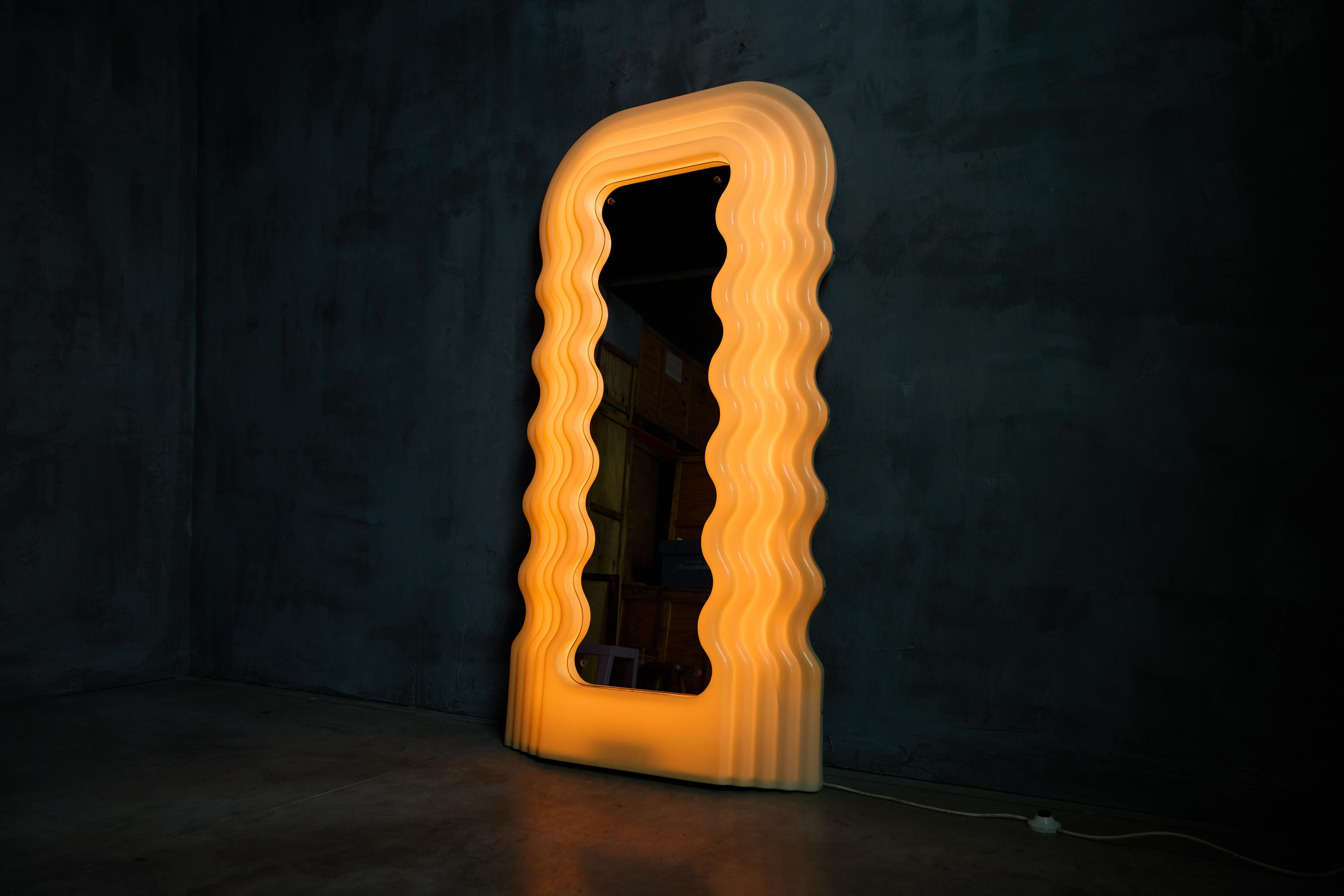 Der ikonische Ultrafragola-Spiegel von Ettore Sottsass ist sowohl ein funktionaler Spiegel als auch ein beleuchtetes Kunstwerk und verkörpert die verspielten, sinnlichen Kurven der Memphis-Bewegung. Ursprünglich wurde er in den 1970er Jahren für