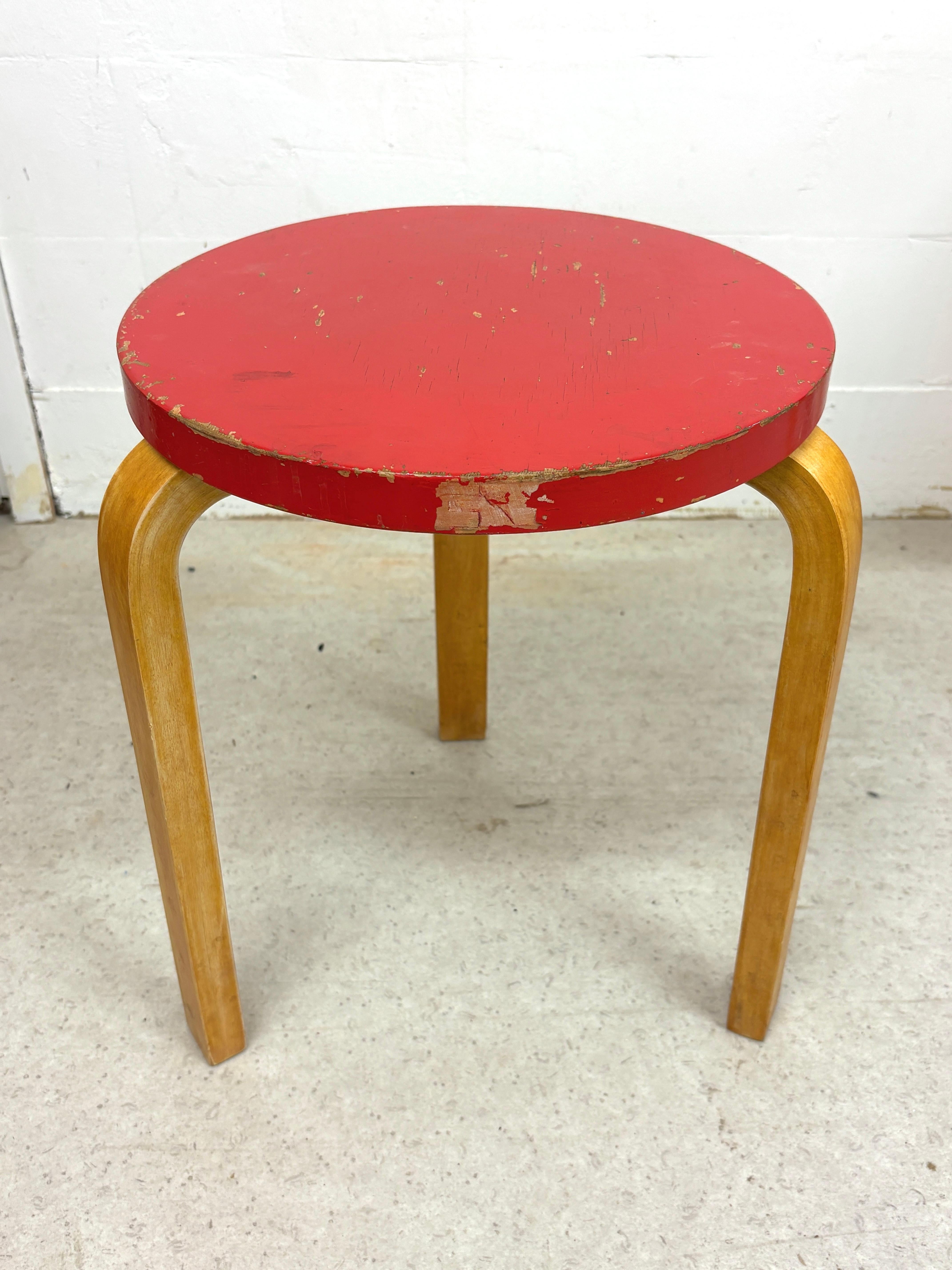 A charming and characterful vintage example of Alvar Aalto’s iconic Stool 60, produced by Artek. This piece features the classic three bent-birch L-legs and a round seat finished in its red lacquer.

Condition:
- Edges and seat show chipping and