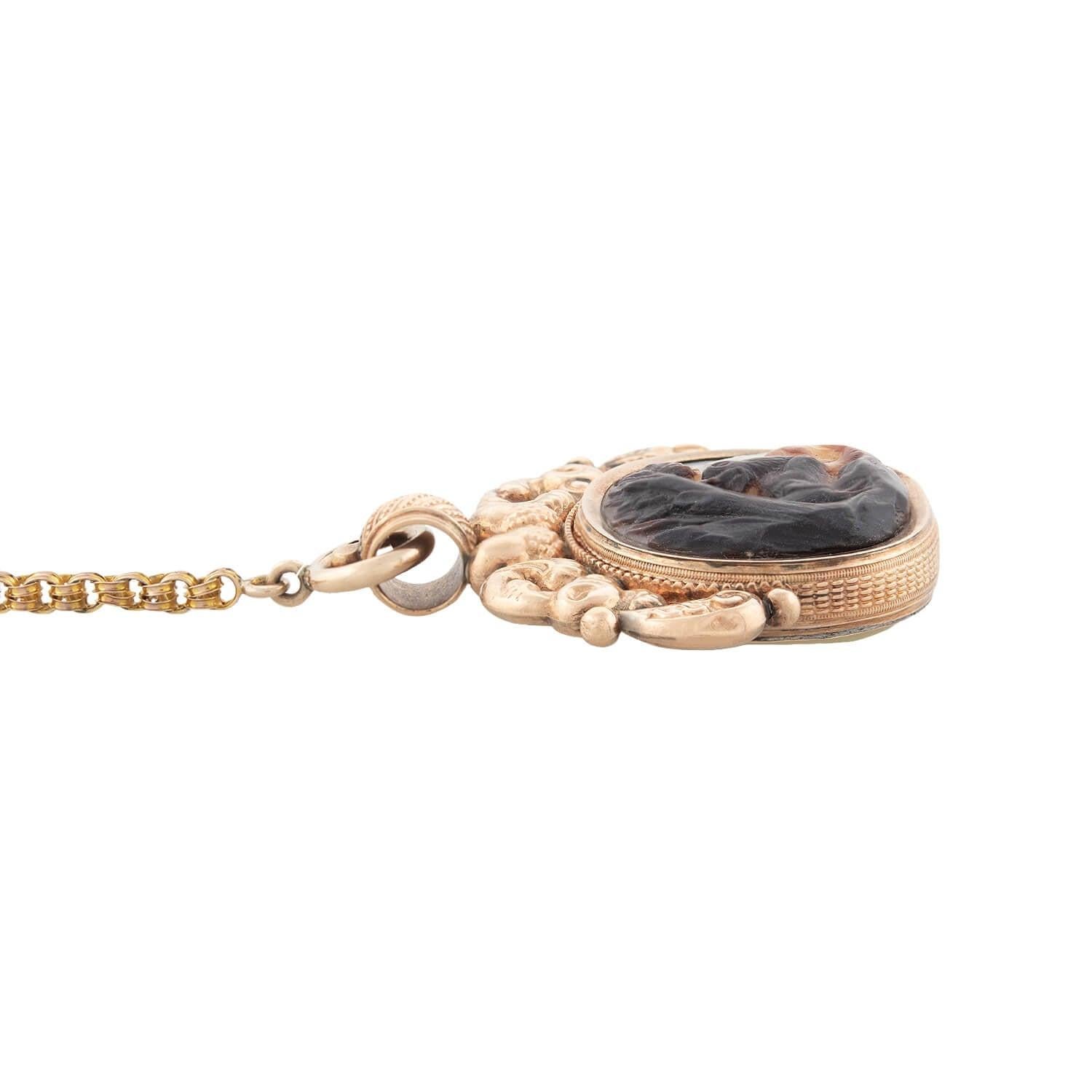 A stunning spinner fob necklace from the Early Victorian (ca1865) era! Crafted in 14kt yellow gold, this spinner fob has an ornate double-sided hand-carved design. One side depicts a bear surrounded by two dogs in a forest setting. The design is