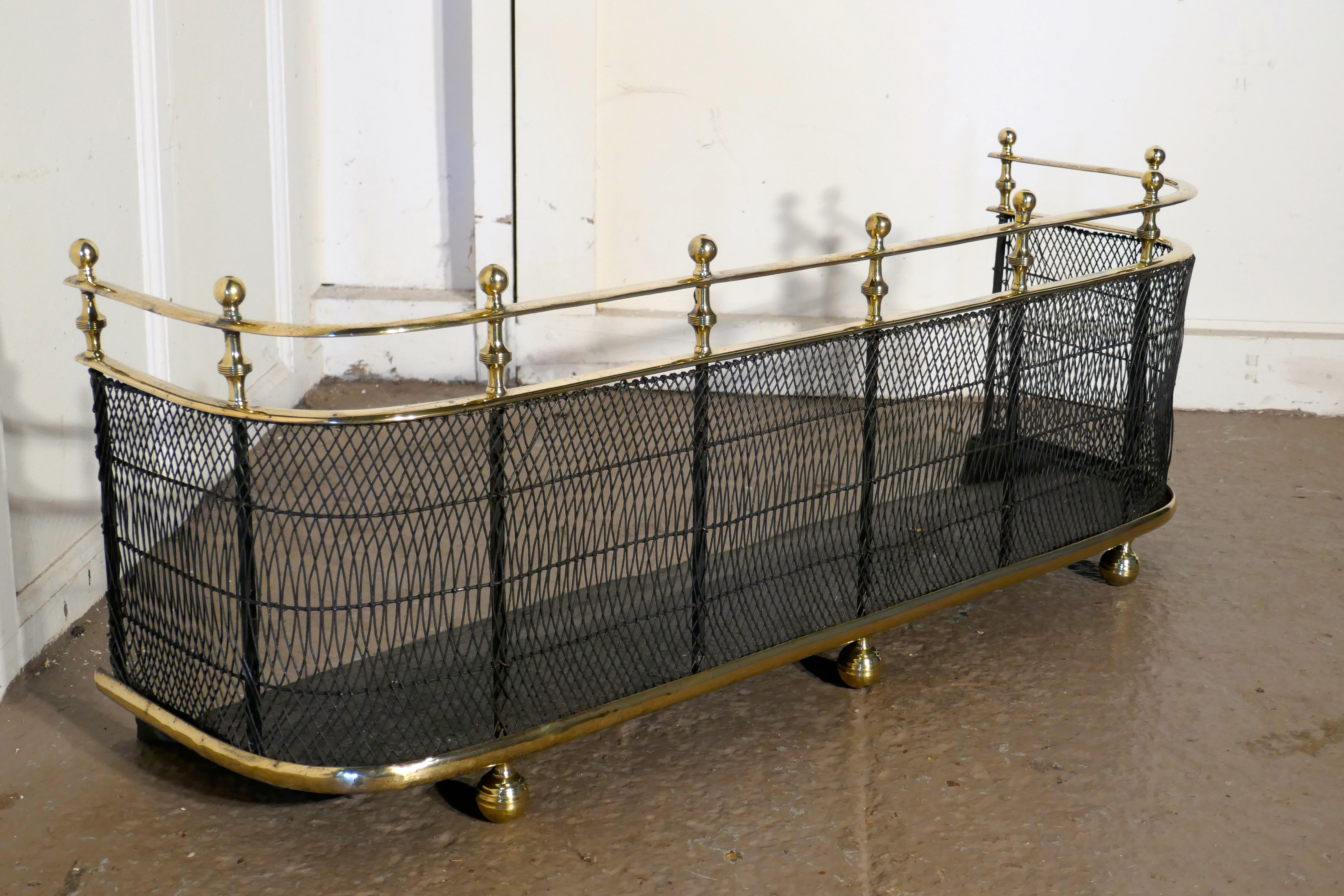 An early Victorian brass and iron fender or fireguard
 
A Victorian antique fire guard often known as a club fender, the iron guard has wire mesh and brass rails top and bottom, it has brass knobs around the top and it stands on brass bun feet,