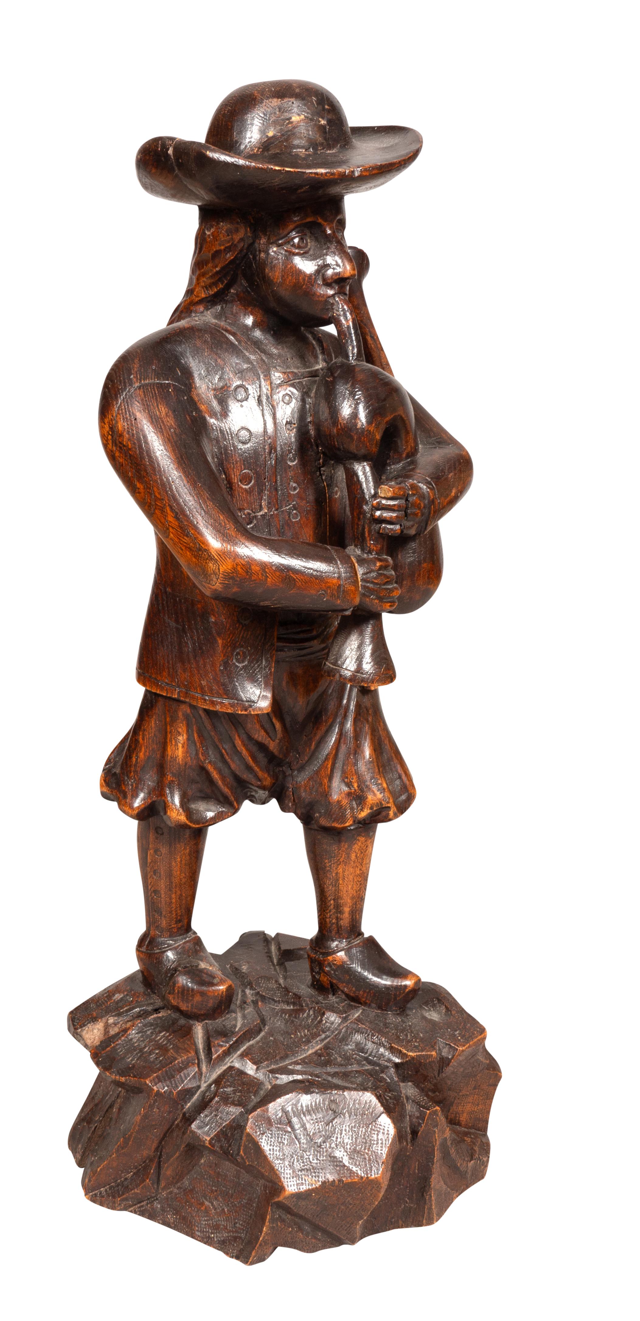 Standing figure with a hat holding and playing a bagpipe on a carved rock work base .Well carved with rich brown patina. Amherst Mass collection.