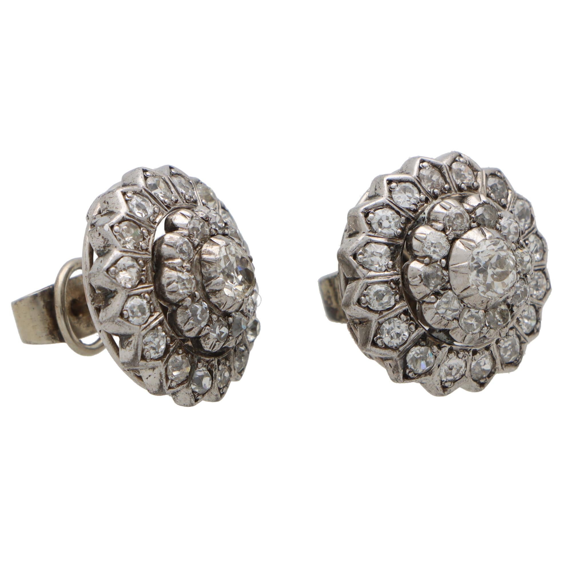 A beautiful pair of Victorian diamond coronet cluster earrings set in silver.

Each earring centrally features a beautiful old mine cut diamond set in a step-down silver setting. The central diamond is then surrounded by two halos of similarly set