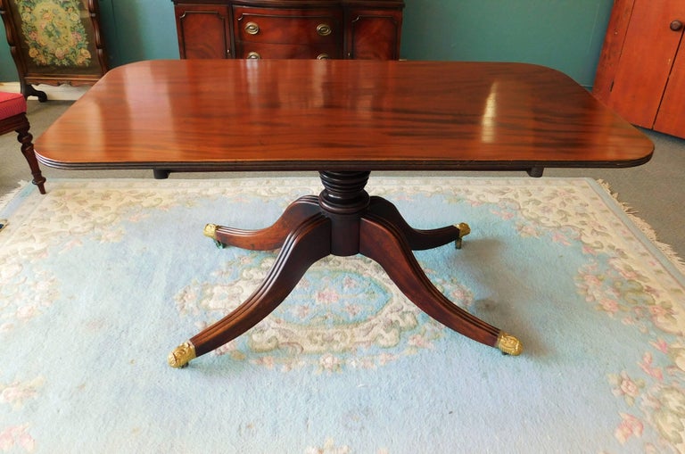 English mahogany tilt-top breakfast table with brass feet and castors. Brass spring loaded catch releases table to upright position, circa 1840.