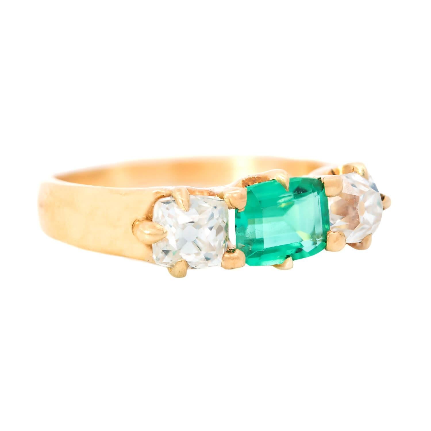 Uno splendido anello con tre pietre, smeraldi e diamanti, risalente all'epoca vittoriana (ca. 1850)! Questo delizioso pezzo fatto a mano è realizzato in oro giallo 14 carati e adorna un singolo smeraldo di grande impatto che riposa tra due
