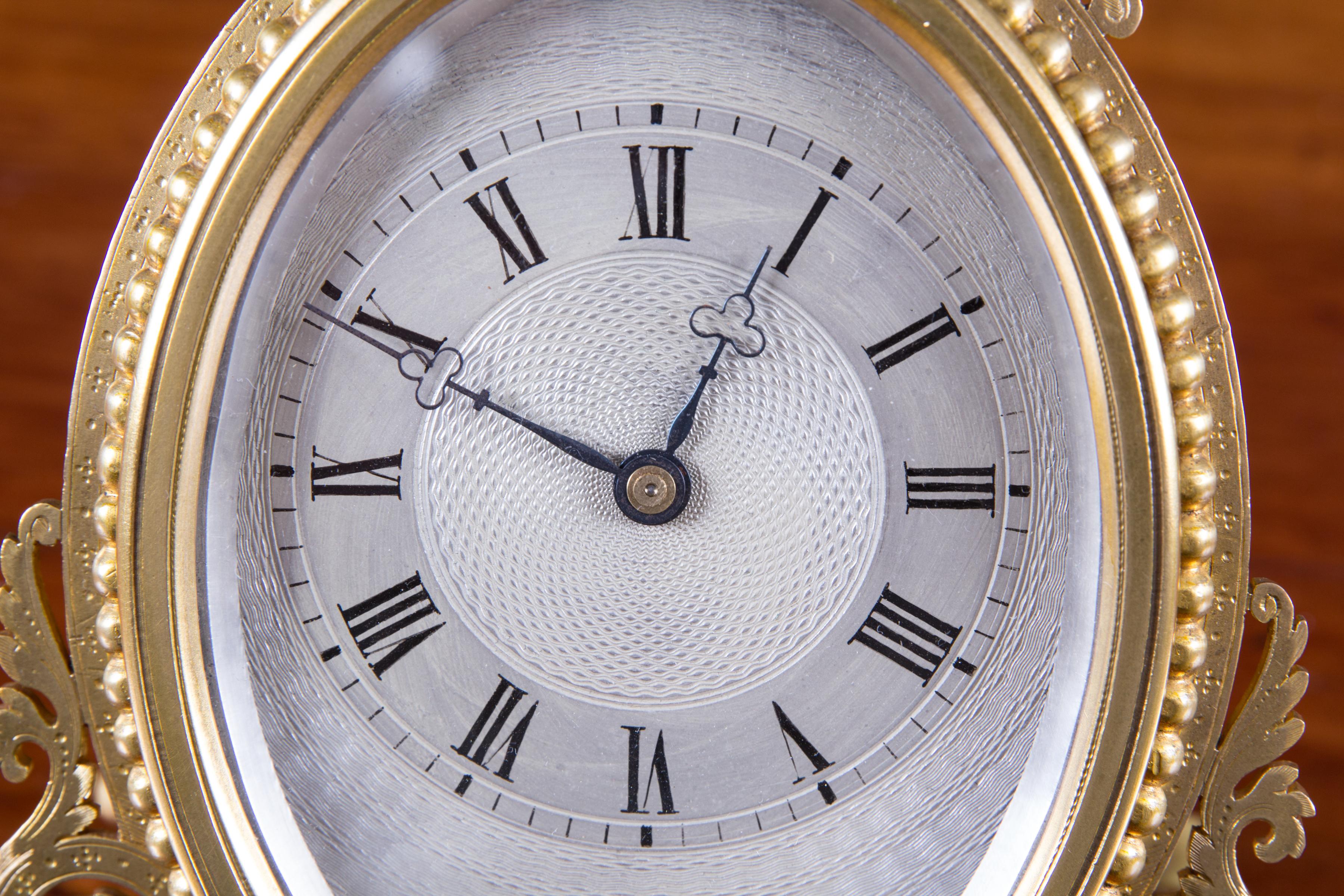 Early Victorian Strut clock in the style of Thomas Cole. 

Gilded frame with engraved scroll work, oval beaded bezel surrounding a beautiful engine turned and silvered dial with Roman numerals and Trefoil hands.

 Eight day French movement with