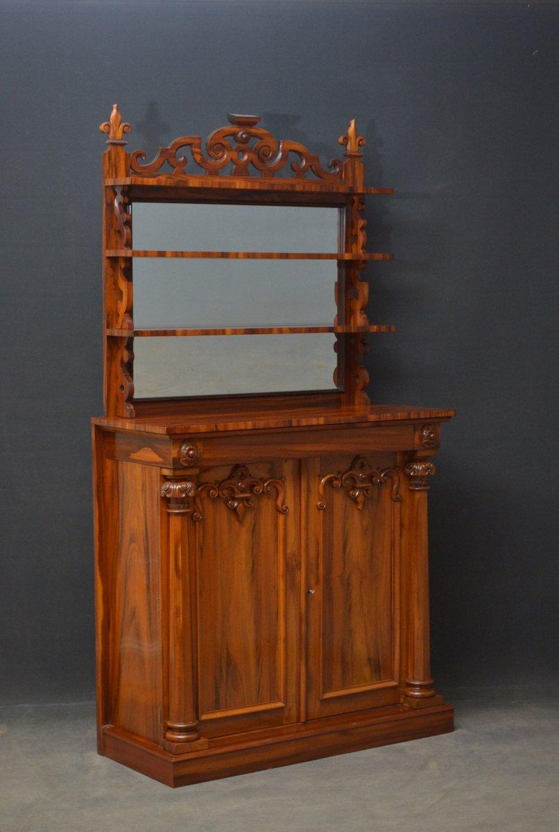 J0 Very unusual goncalo alves tall chiffonier, having mirrored back with 3 shelves, carved upstand and shaped supports over stunning top with secret frieze drawer above a pair of panelled and carved doors enclosing 2 shelves and fitted with working