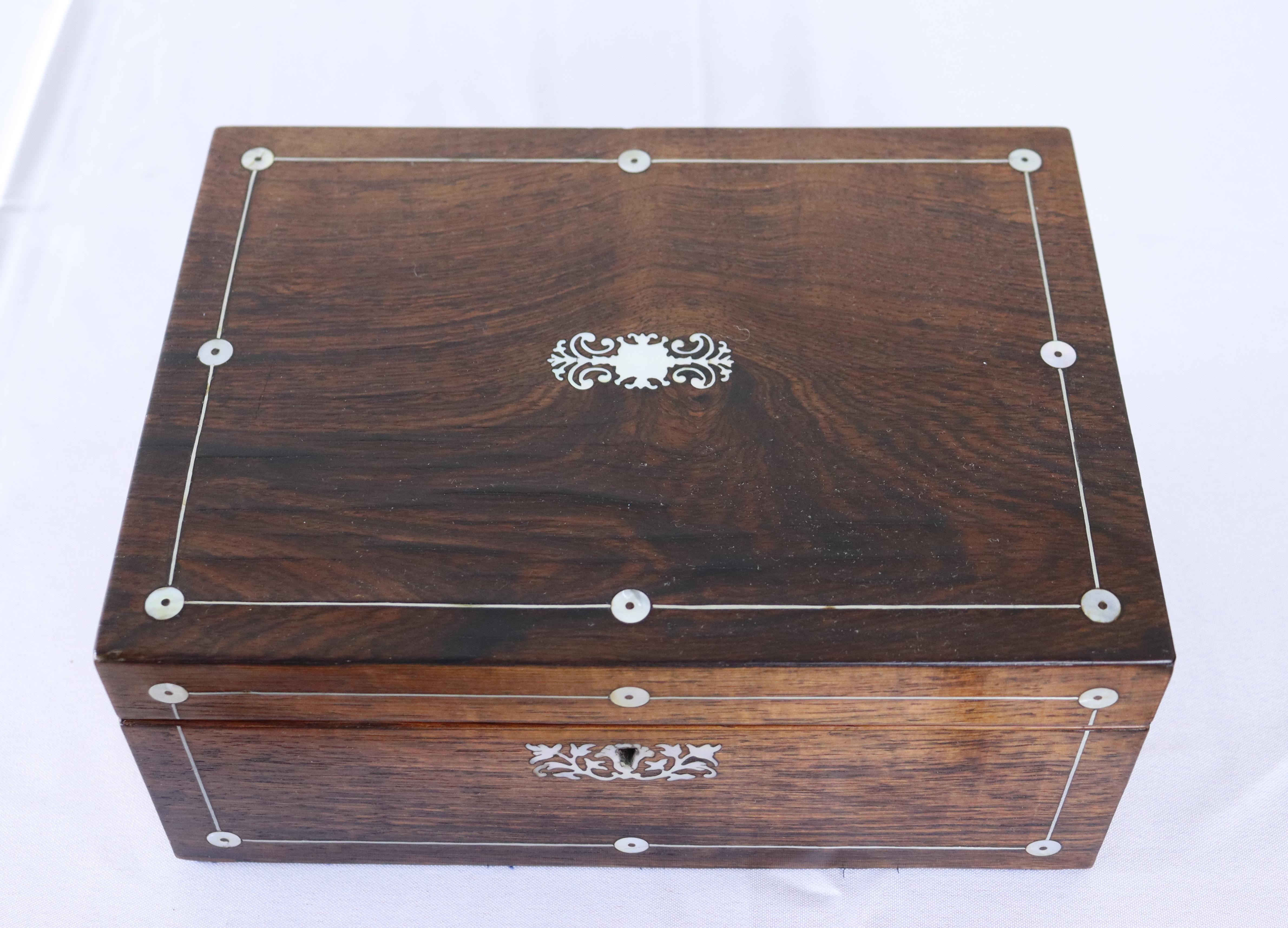 A lovely rosewood box from the Victorian period, beautifully inlaid with mother-of-pearl.  The interior has been lined with fresh watered paper, and is clean.  In lay is in good condition.  No key.