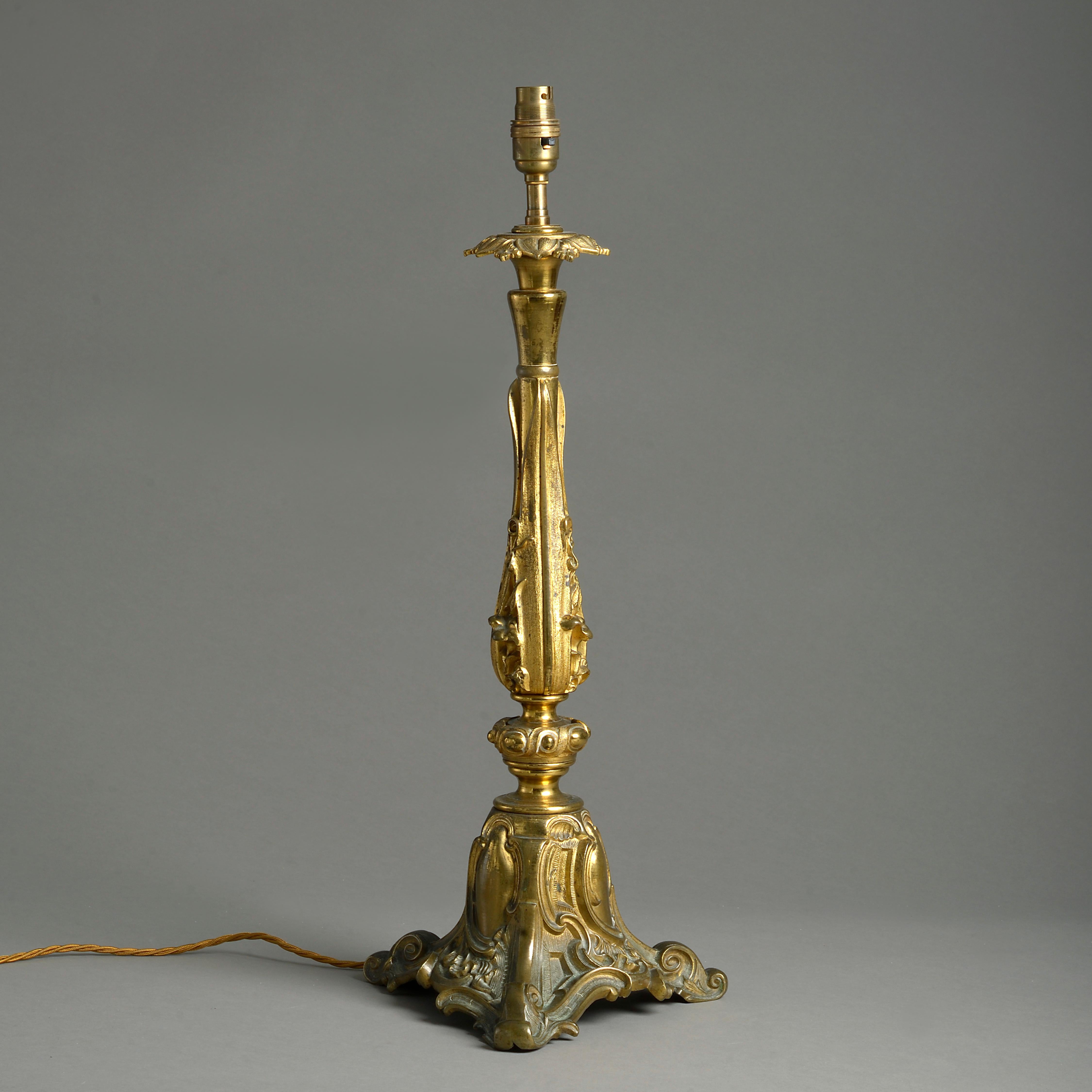 An early Victorian lacquered brass table lamp elaborately cast with foliage and scrolls on a tripod base, circa 1850.
   