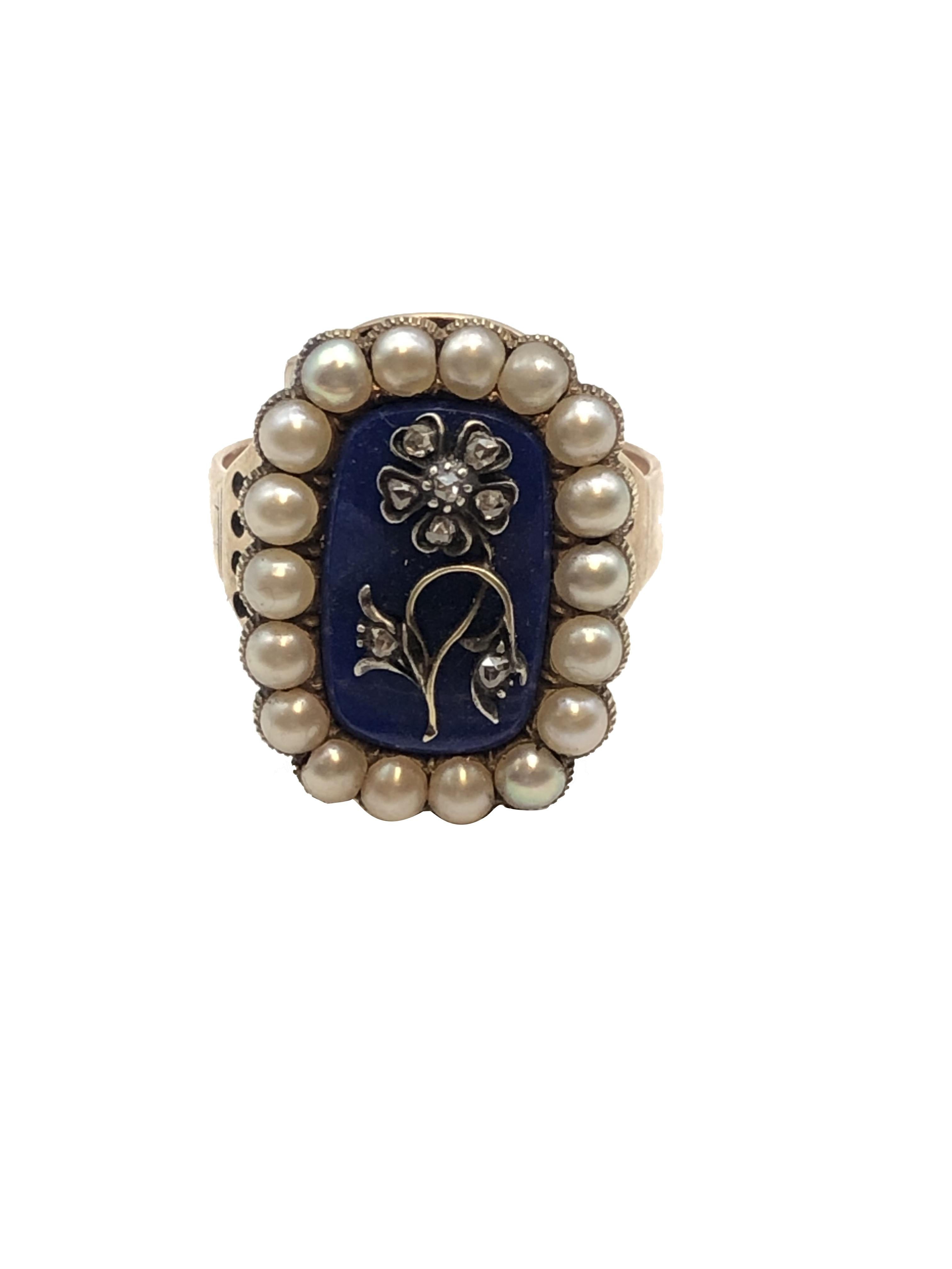 Circa 1850s Ladies Ring, the top measuring 7/8 X 5/8 inch with a Center of Lapis Lazuli mounted with a silver flower set with Rose cut Diamonds and further surrounded by Natural Pearls. Finger size 11. 