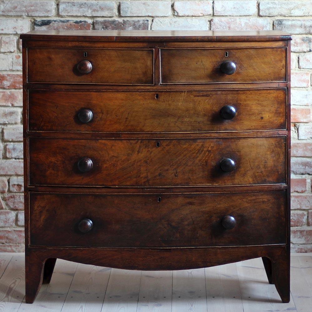Early Victorian mahogany chest of drawers made in England in 19th century. The piece features three long mahogany drawers with original turned mahogany knobs and two smaller ones in the highest section providing lots of storage space. The chest has