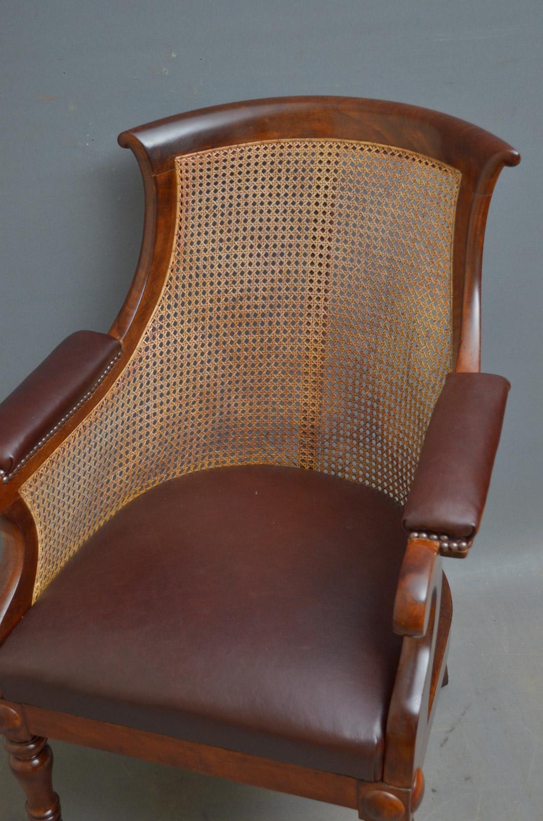 Sn4396, stylish early Victorian mahogany bergère library chair, having curved top rail with scrolled and leather padded arms, caned back and generous leather seat, standing on turned legs terminating in original brass castors. This caned armchair is
