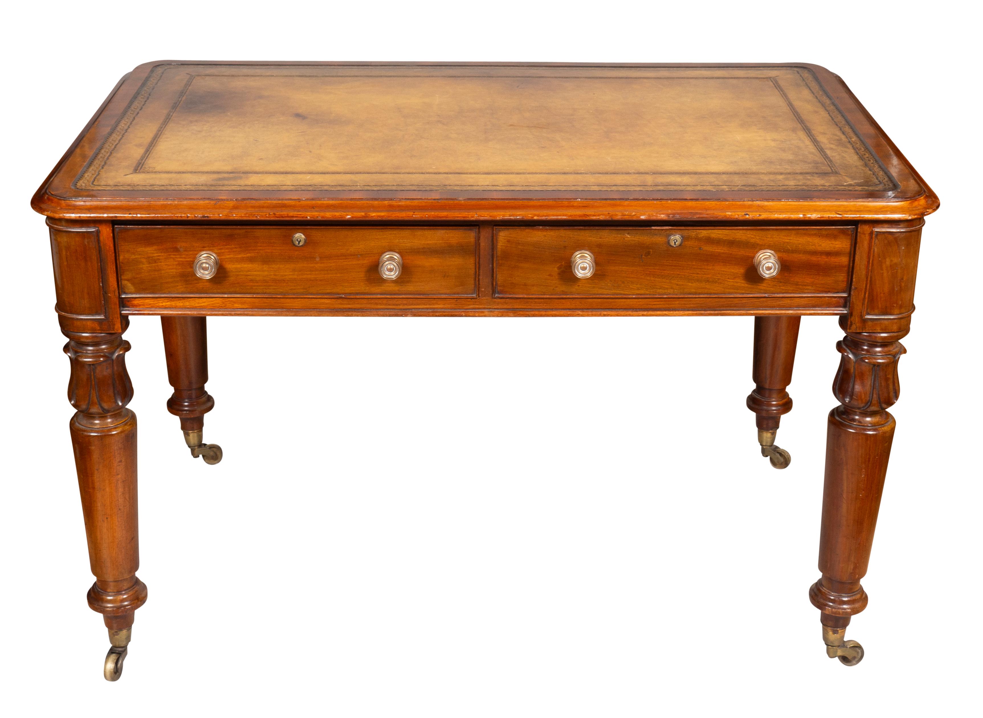 Typical form with rectangular top with inset brown leather over two drawers flanked by rounded paneled ends, raised on lotus carved turned tapered legs and casters.