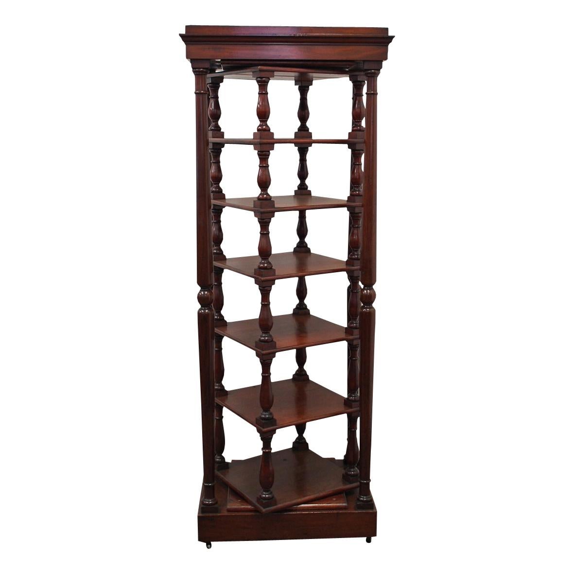 Rare full-size early Victorian revolving whatnot. The outer frame in figured mahogany has a rectangular top with moulded edge, supported on tall turned columns. This is over a deep plinth base which is finished on castors. Internally the six-tier