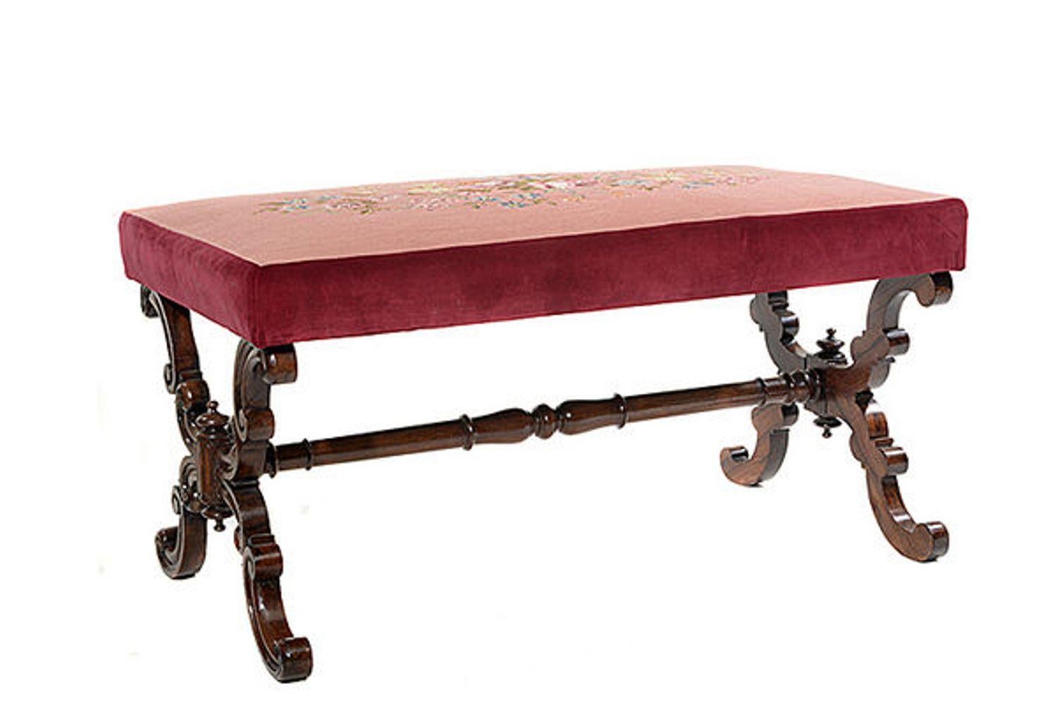An early Victorian rosewood X framed stool covered with a hand worked floral tapestry  on a pink background and with a red velvet border.

The moulded and scrolling X frame side supports are united by a tapering ring turned central stretcher.