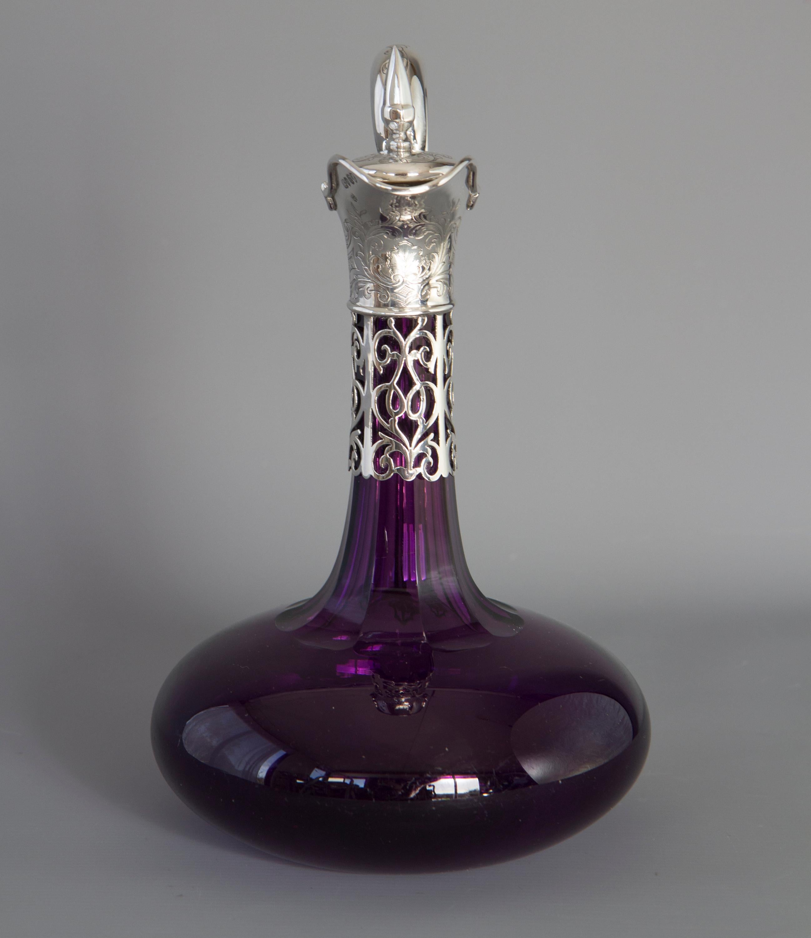 A highly unusual very early Victorian silver mounted amethyst glass claret jug or wine decanter of circular bellied form.
The purple glass body with a narrow octagonal neck featuring a silver mount with pierced scrolling pattern and a bifurcated
