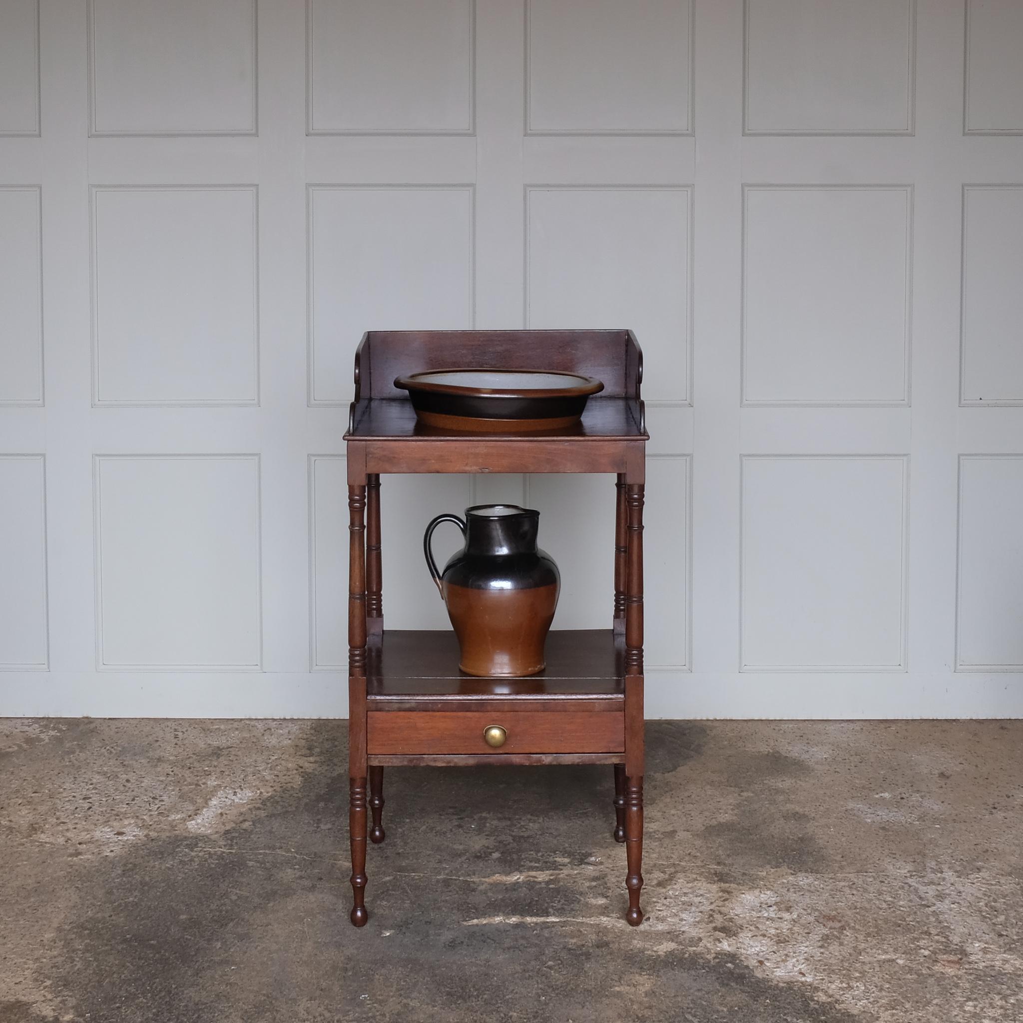A charming early Victorian mahogany washstand, the three quarter gallery with a basin recess on turned and ringed uprights, over a single shelf with drawer over turned and ringed legs, also comprising a later stoneware basin and jug, with a gentle