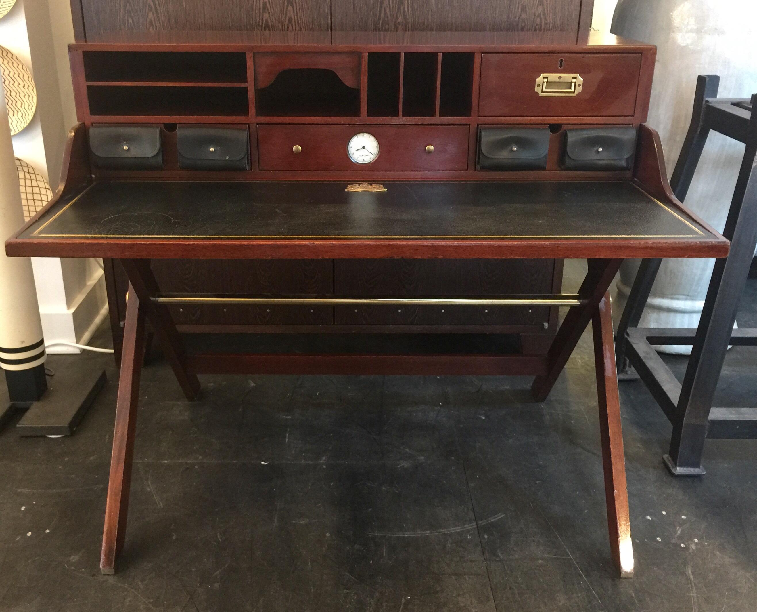 A Classic and masculine Ralph Lauren mahogany campaign desk which sits atop an X-base with brass stretcher. The writing table is covered in a rich black leather blotter with RL embossed logo. Brass handles to sides of drawers cabinet providing 4