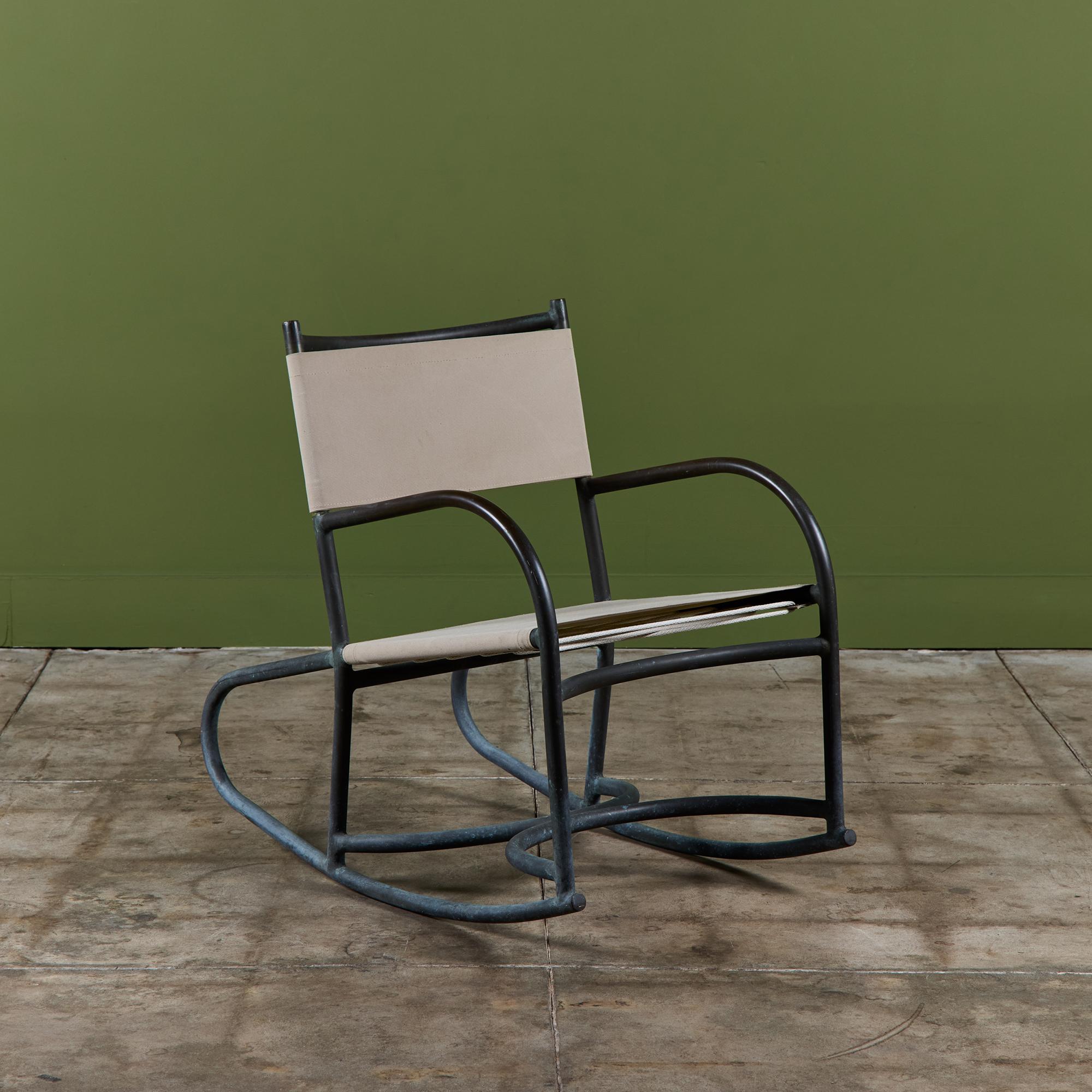 The late 1940s or early 1950s Walter Lamb rocking chair predating his partnership with Brown Jordan. The chair has a frame in thick tubular bronze. Two runners with bowed rear edges form the rocking frame, which terminates on either side of the