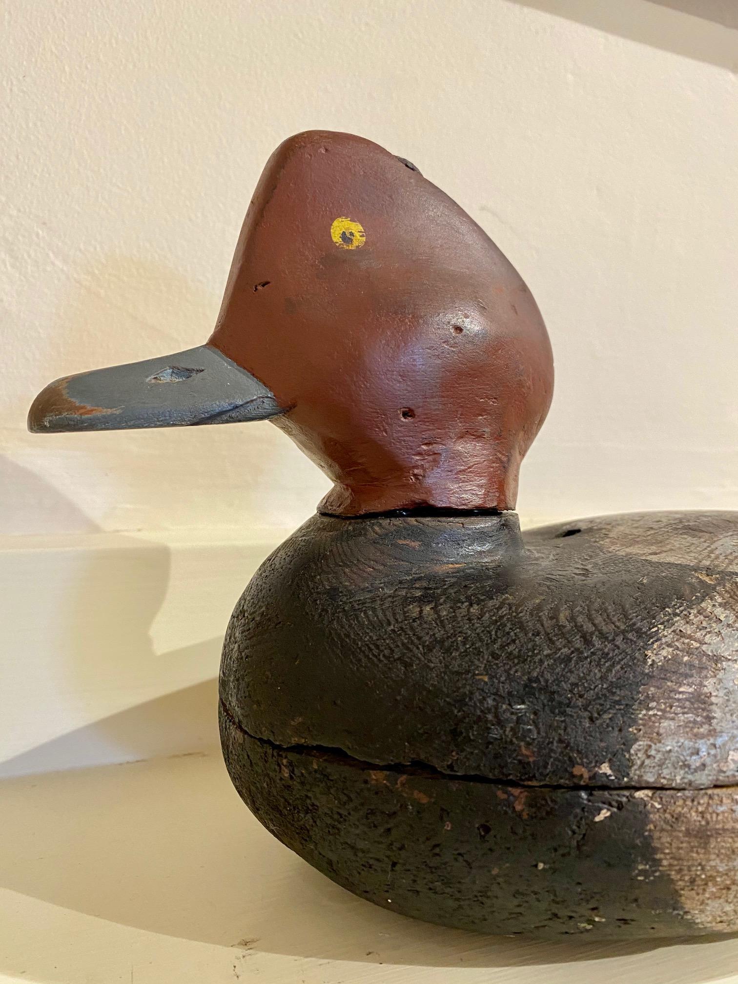 Antique Ward Brothers red head drake decoy, early period, circa 1930, having a hand carved hollow body, a distinctly shaped head with painted yellow eyes and carved nares and bill gape, and a small paddle tail, in worn original paint. This decoy has