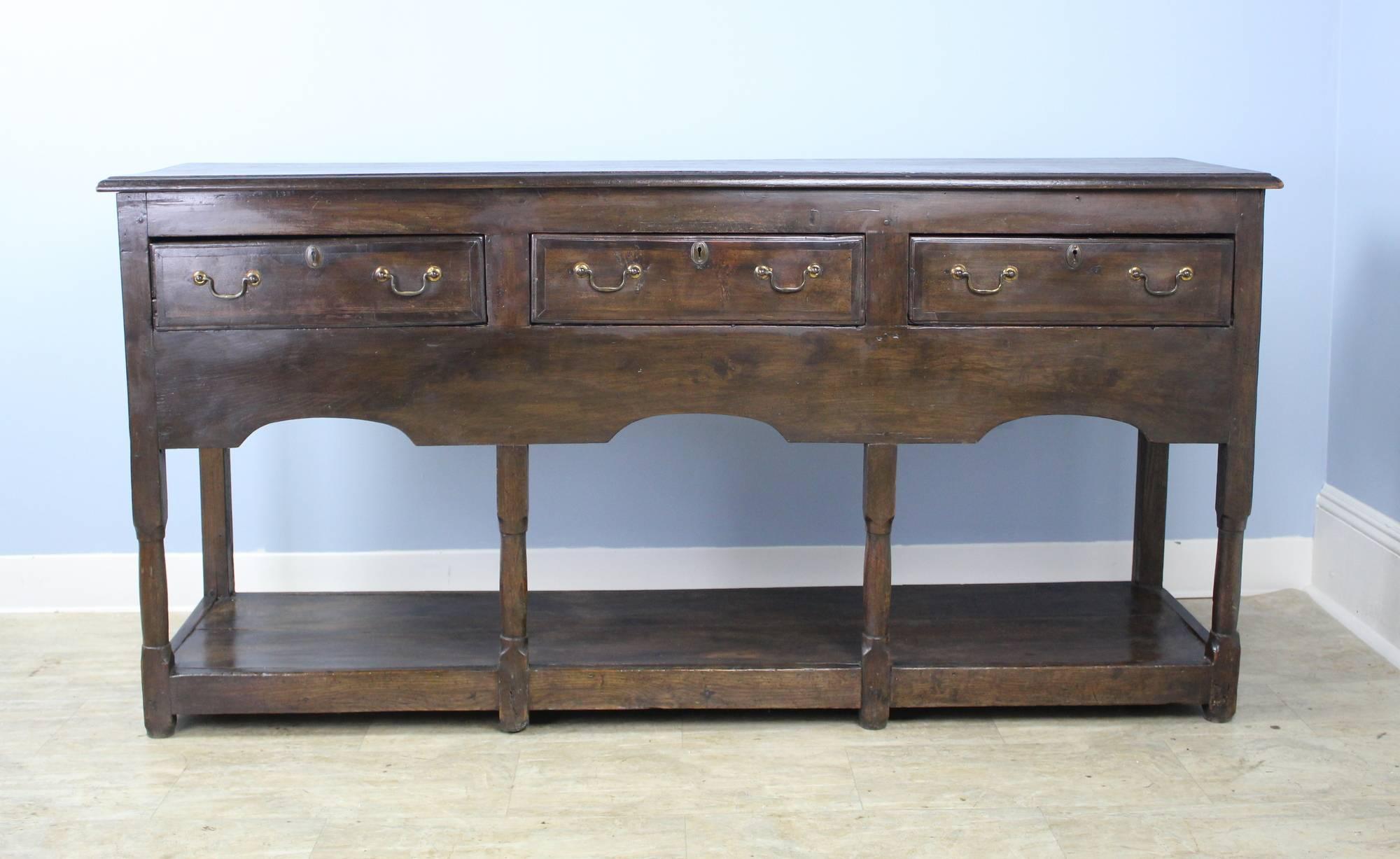 With fine strong molding around the top of the drawer section, and well carved scallop detail at the apron, this console is an excellent example of classic early Welsh period furniture. The legs are neatly turned, and the all-around pot board base