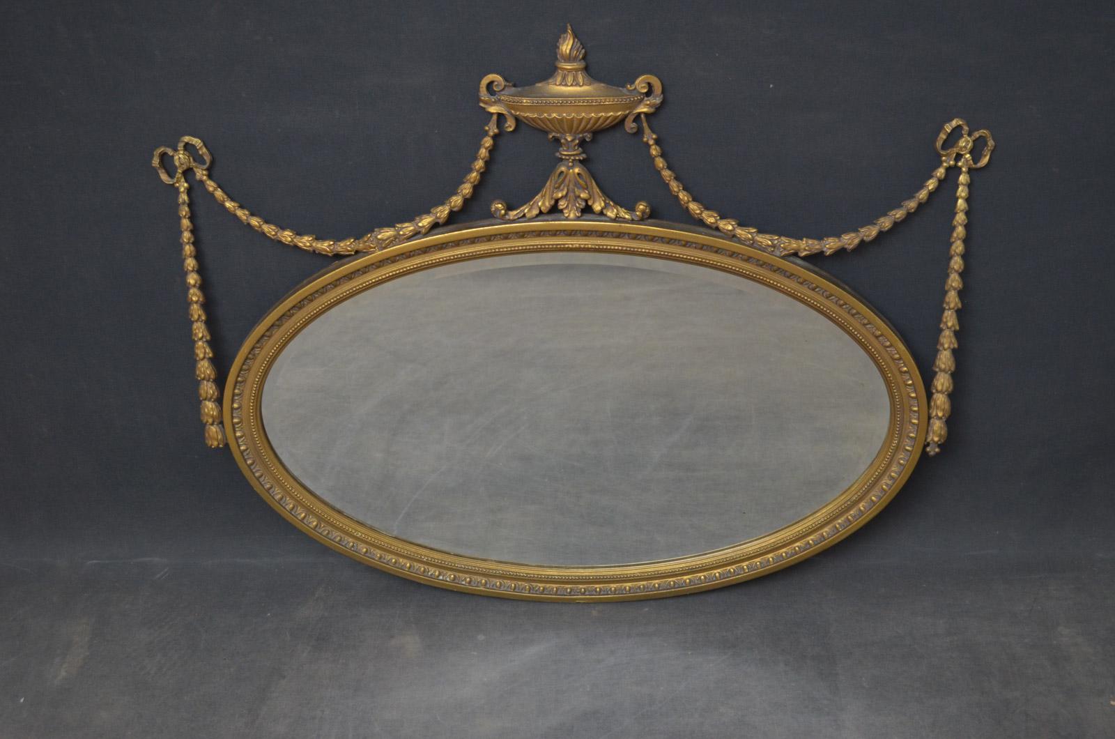 Sn4622 Adam Revival wall mirror of oval form, having original bevelled edge mirror in egg and dart decorated frame with centre finial flanked by bows and swags. This antique mirror has been refinished, it is in excellent home ready condition, circa